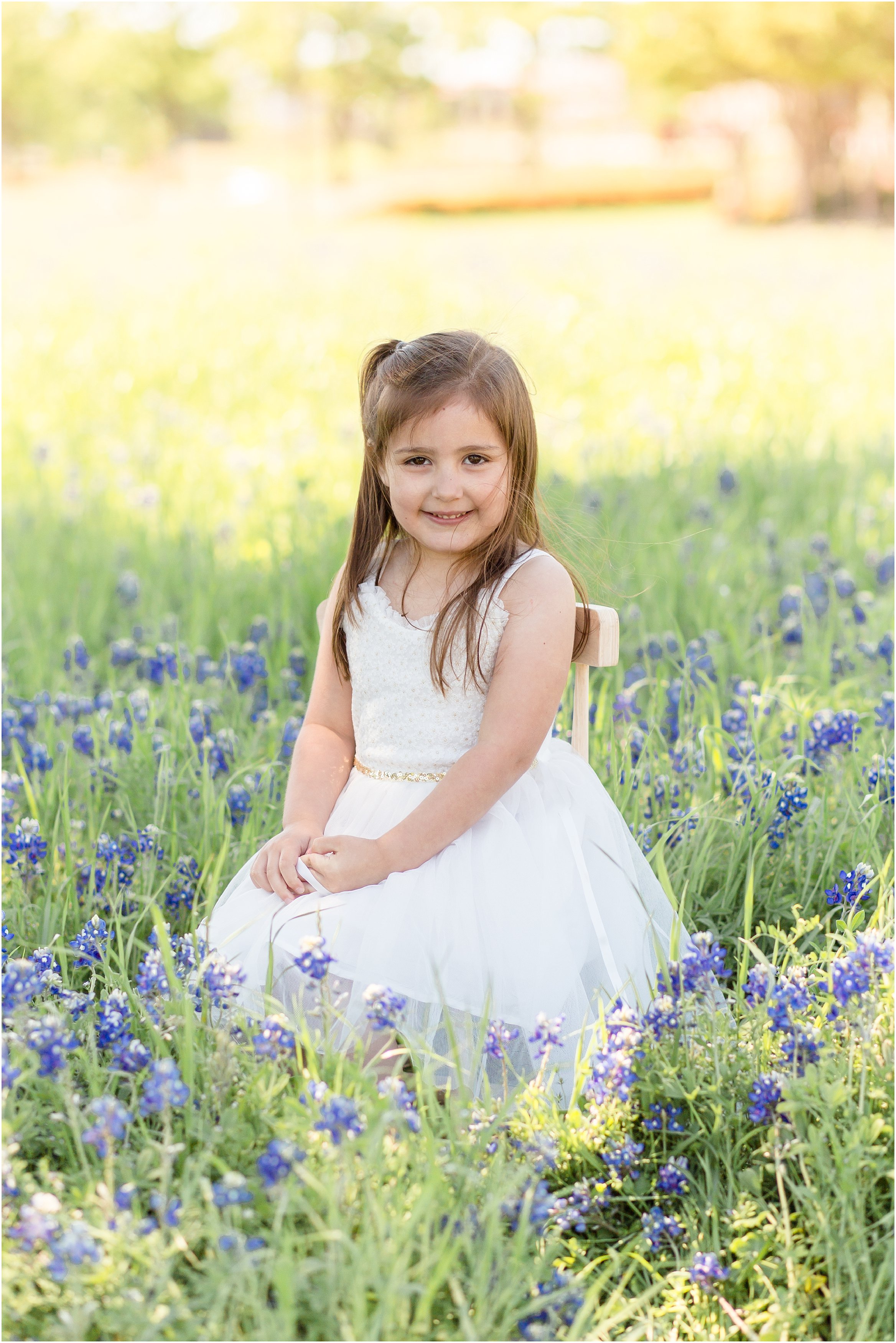 little girl in a white dress in a bluebonnet field