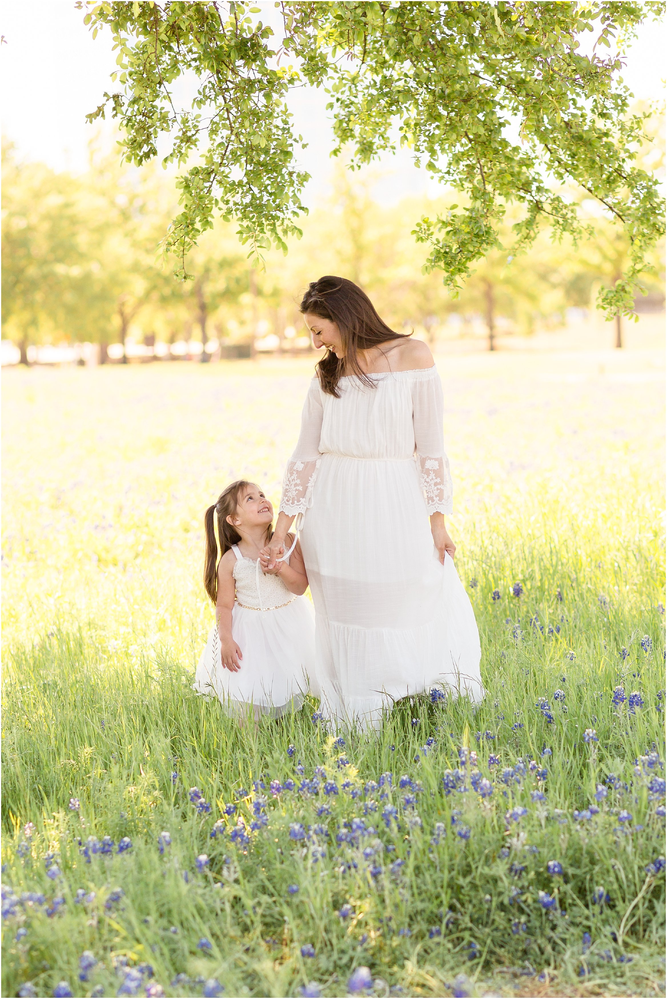 mom and daughter in white dresses in field