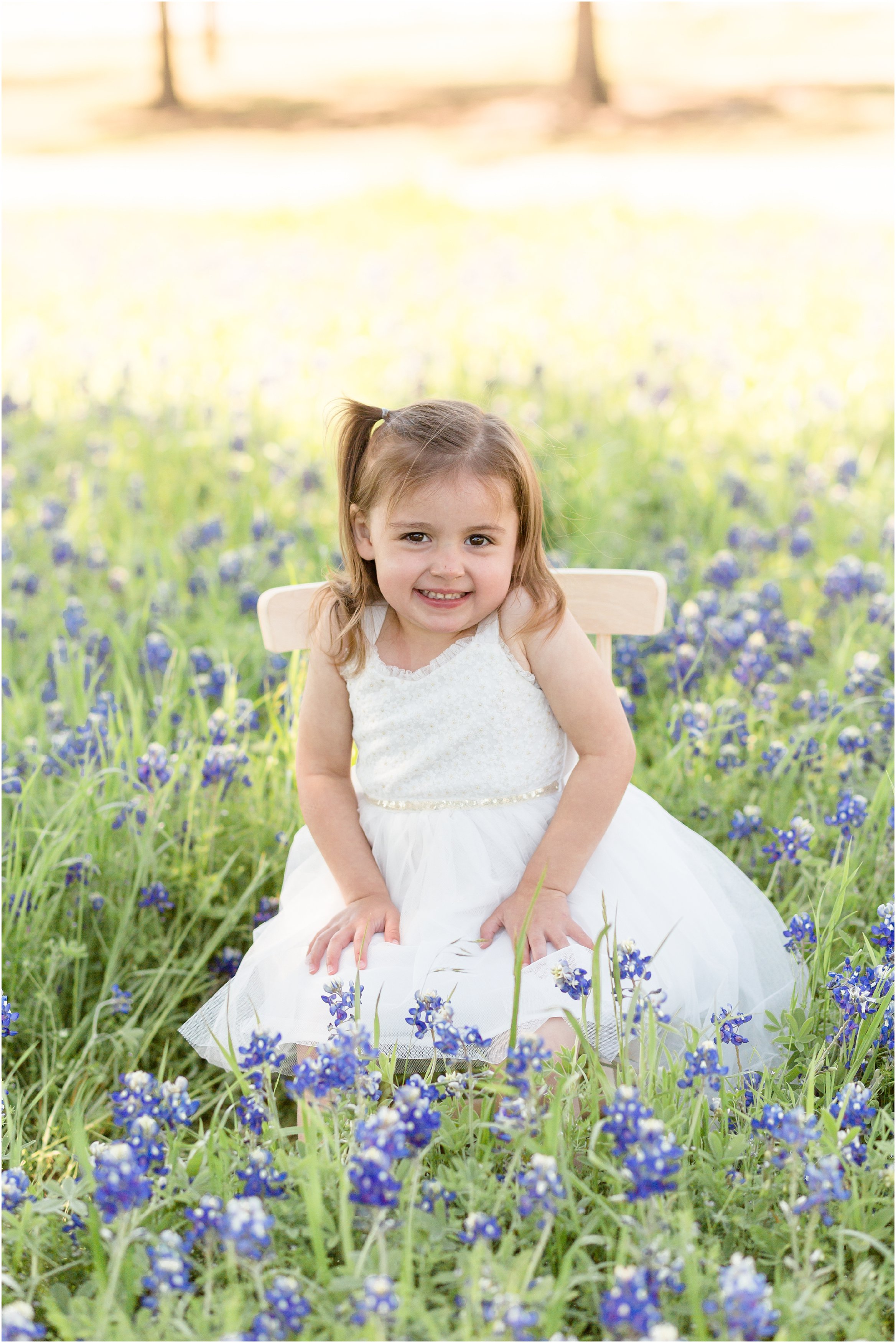 little girl in a white dress in a bluebonnet field