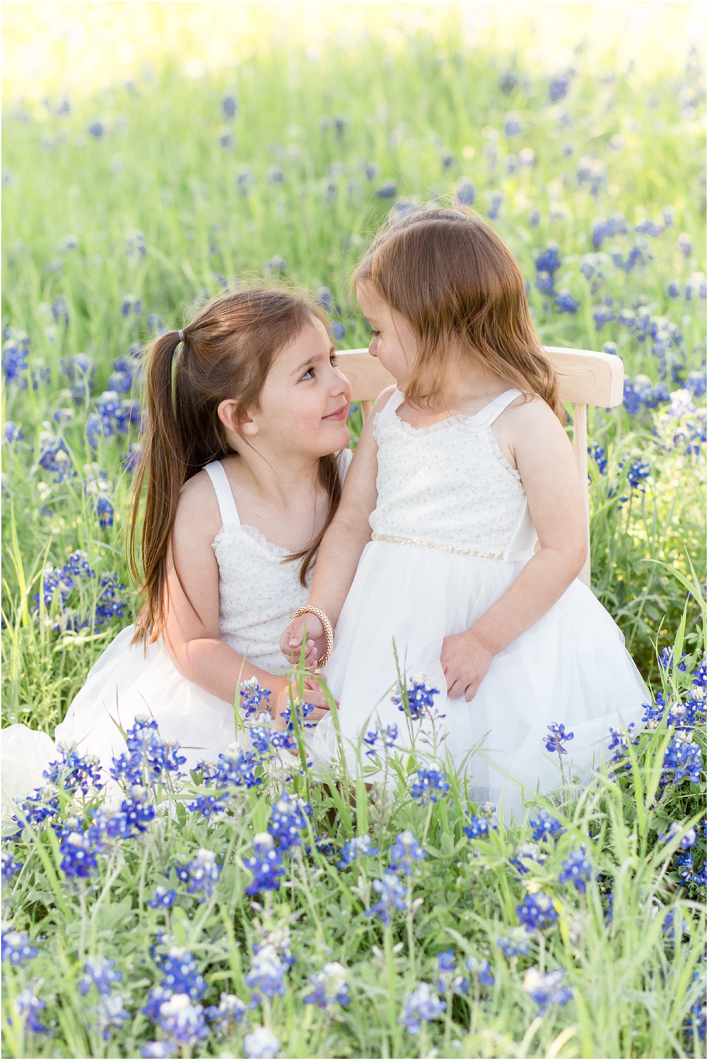 sisters in white dresses in a bluebonnet field
