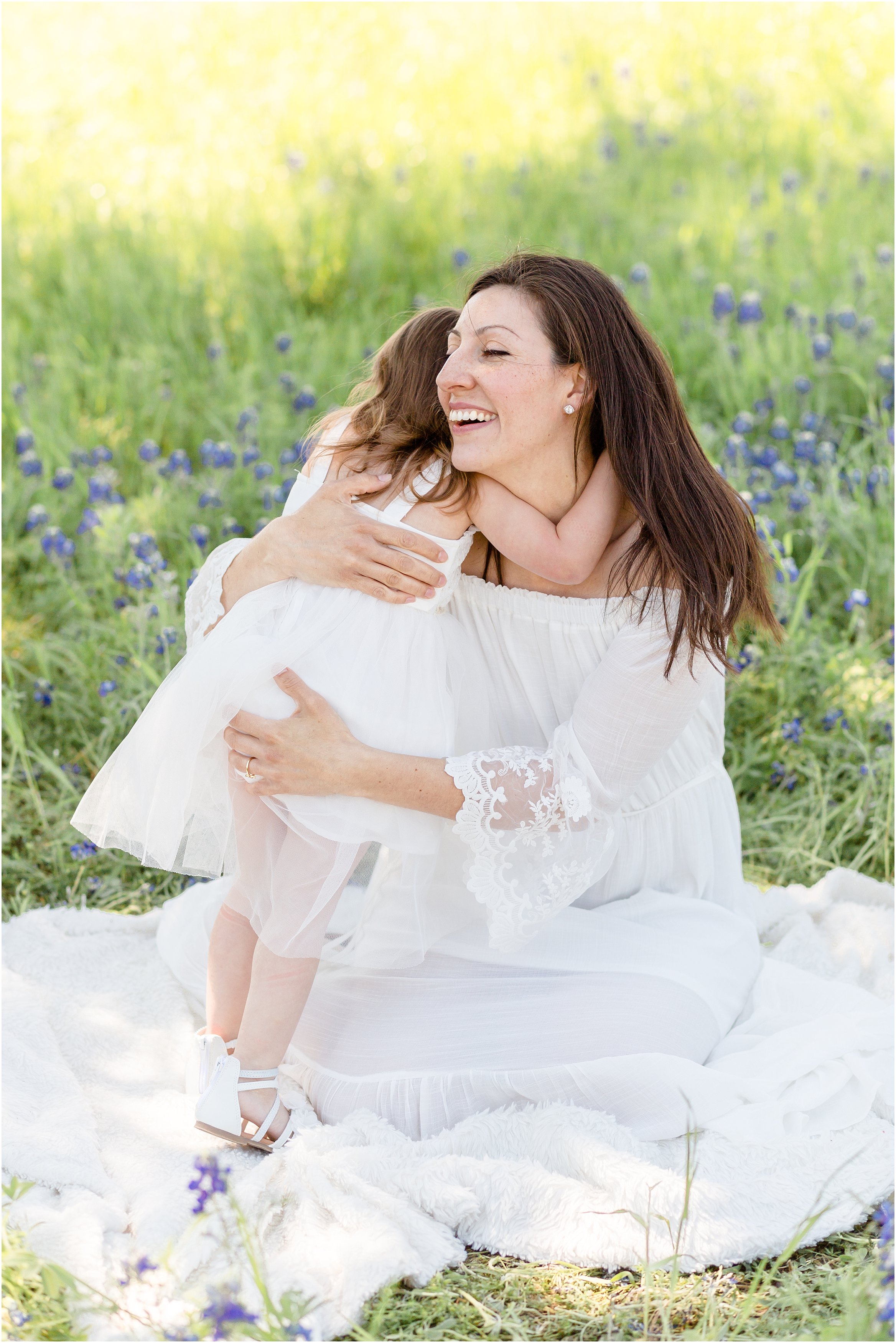 mom and daughter in white dresses in a bluebonnet field