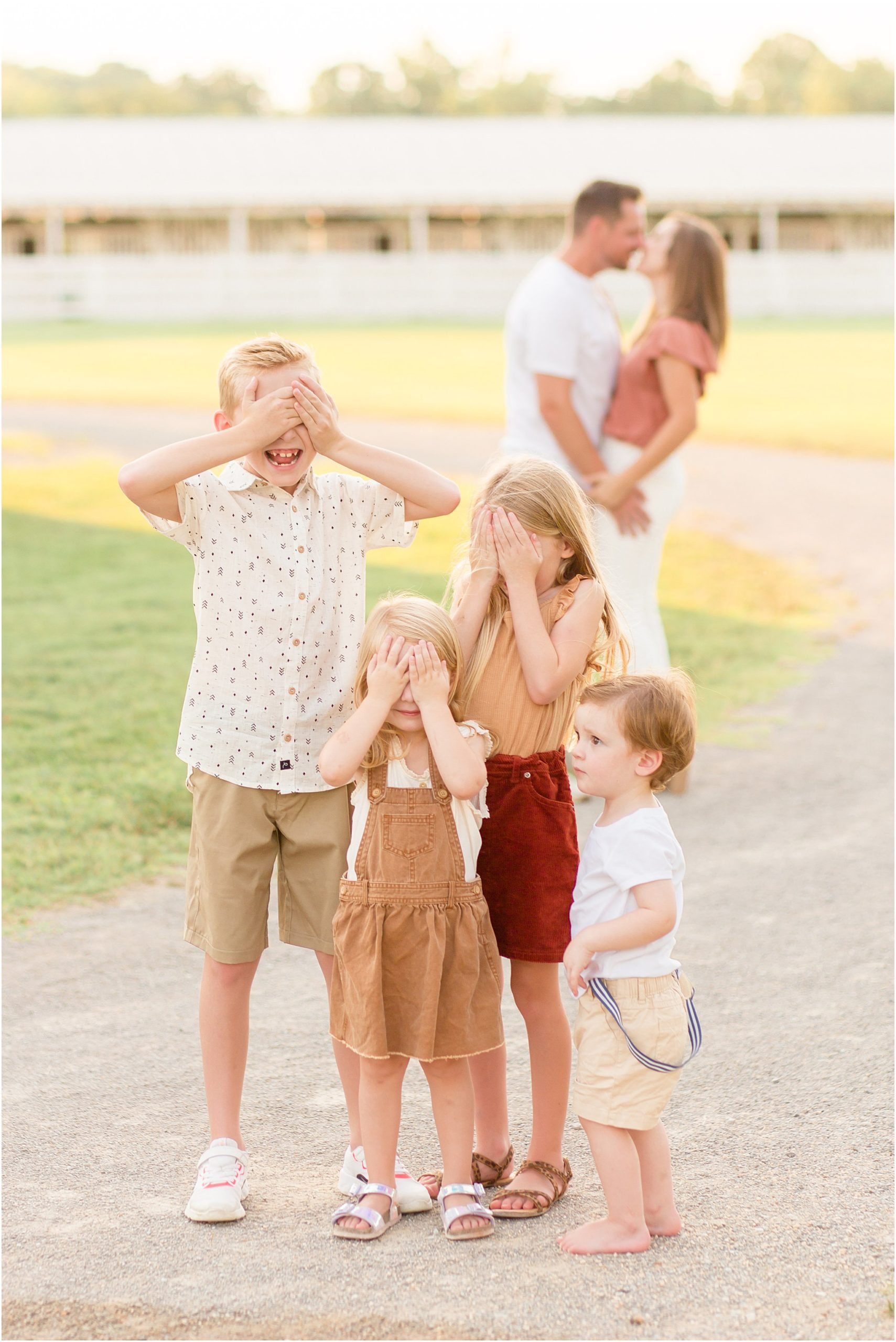 4 kids with parents kissing at harlinsdale farms in franklin tn by nashville family photographer