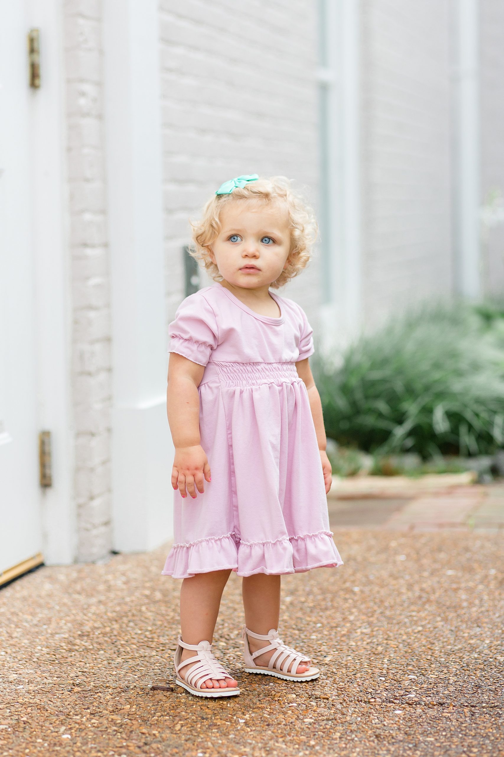 toddler in pink dress stands outside church