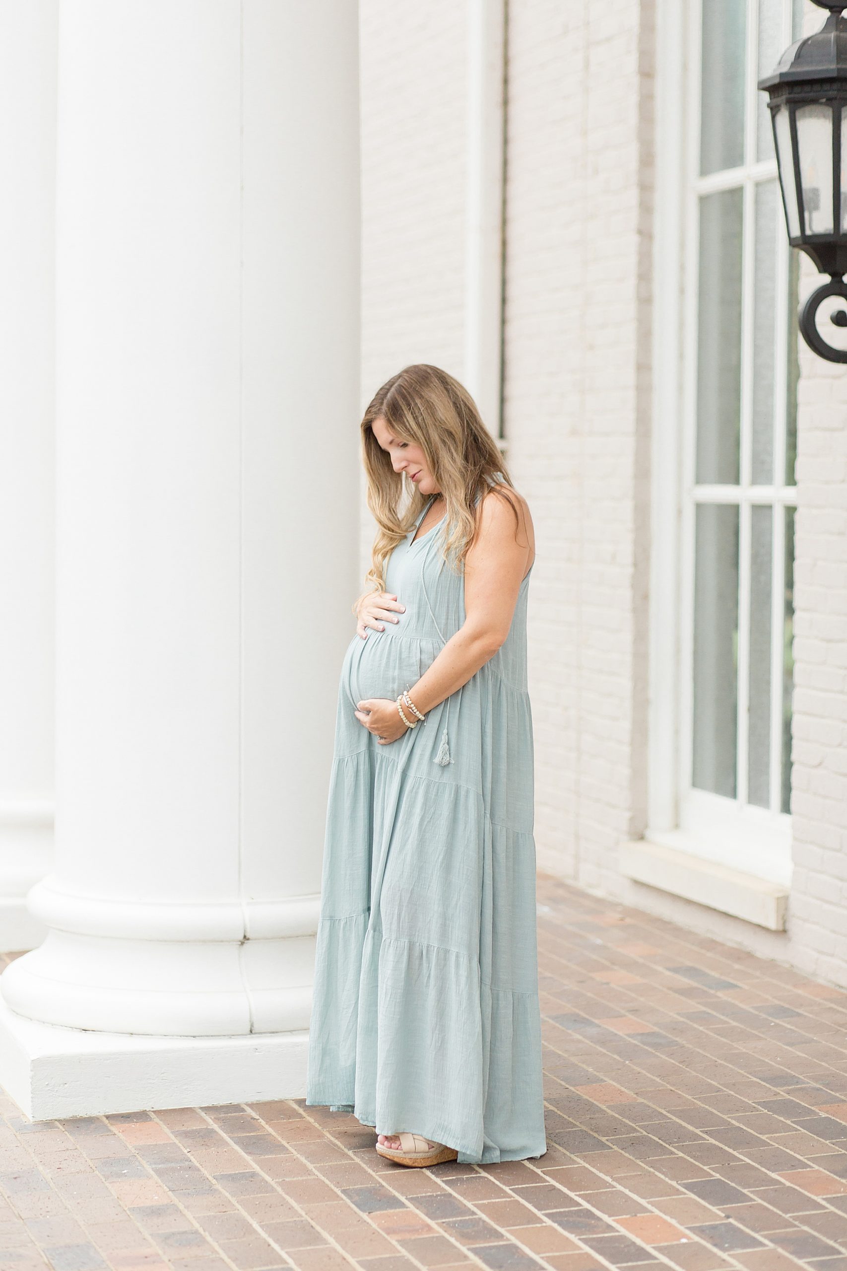 Pregnant mom holds belly while wearing green dress