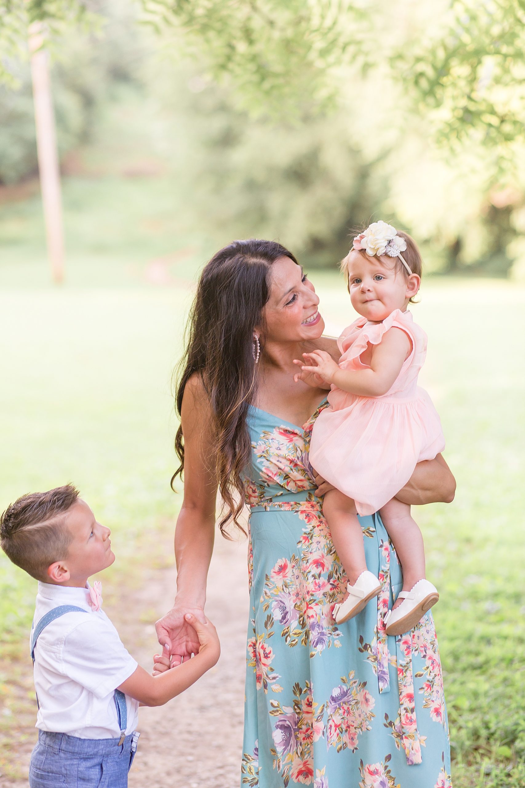 mom talks to daughter in pink dress while holding son's hand