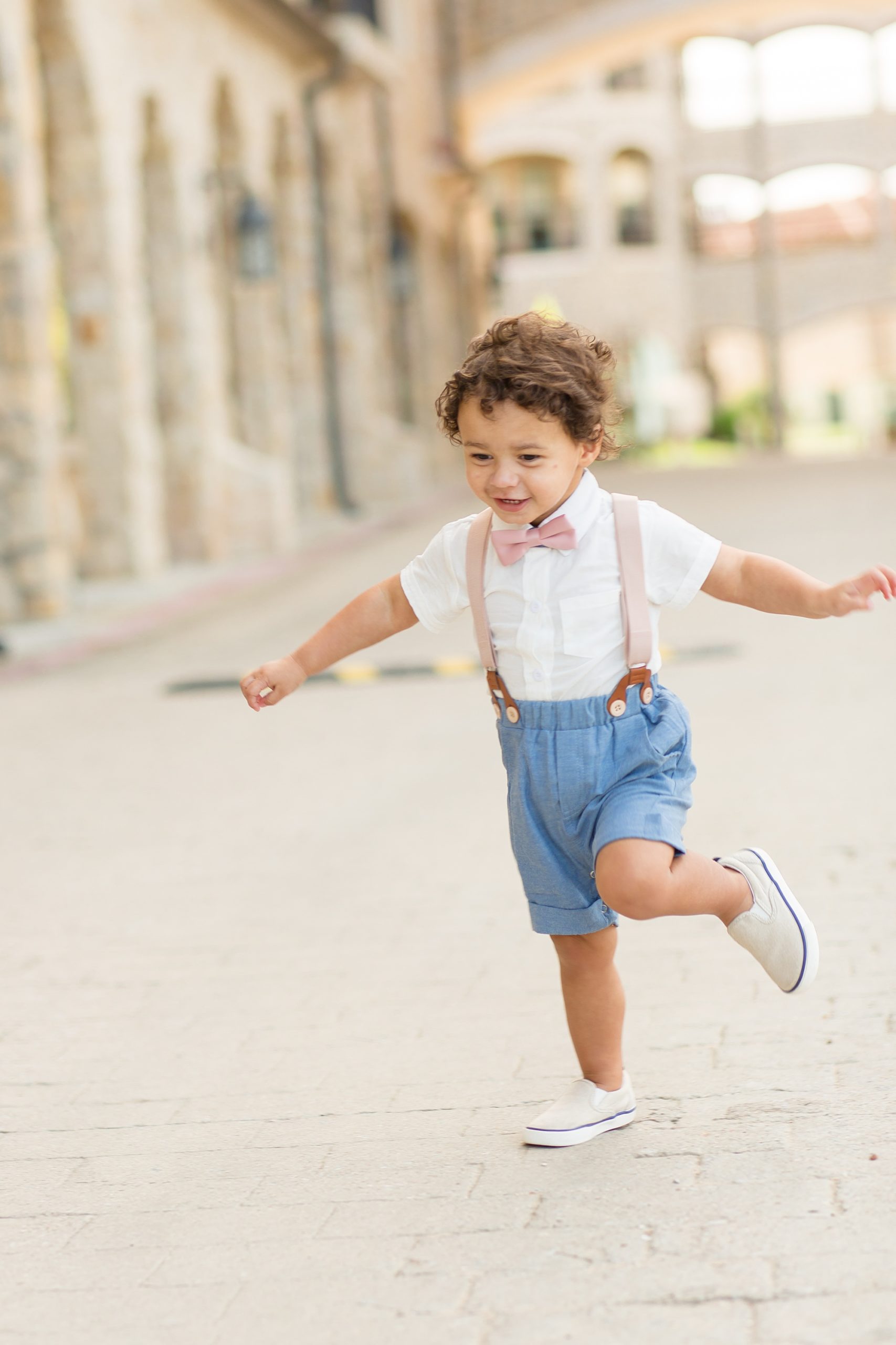 toddler in suspenders runs through Adriatica Village