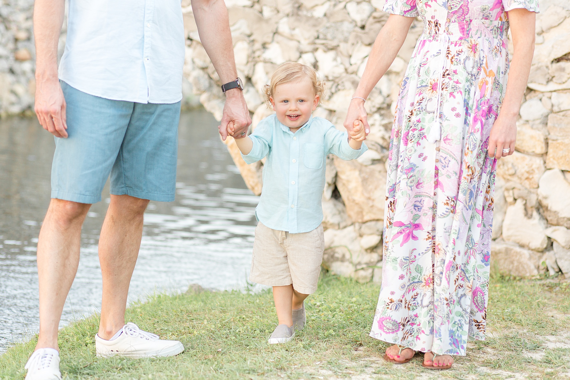toddler holds parents hands and walks through Adriatica Village