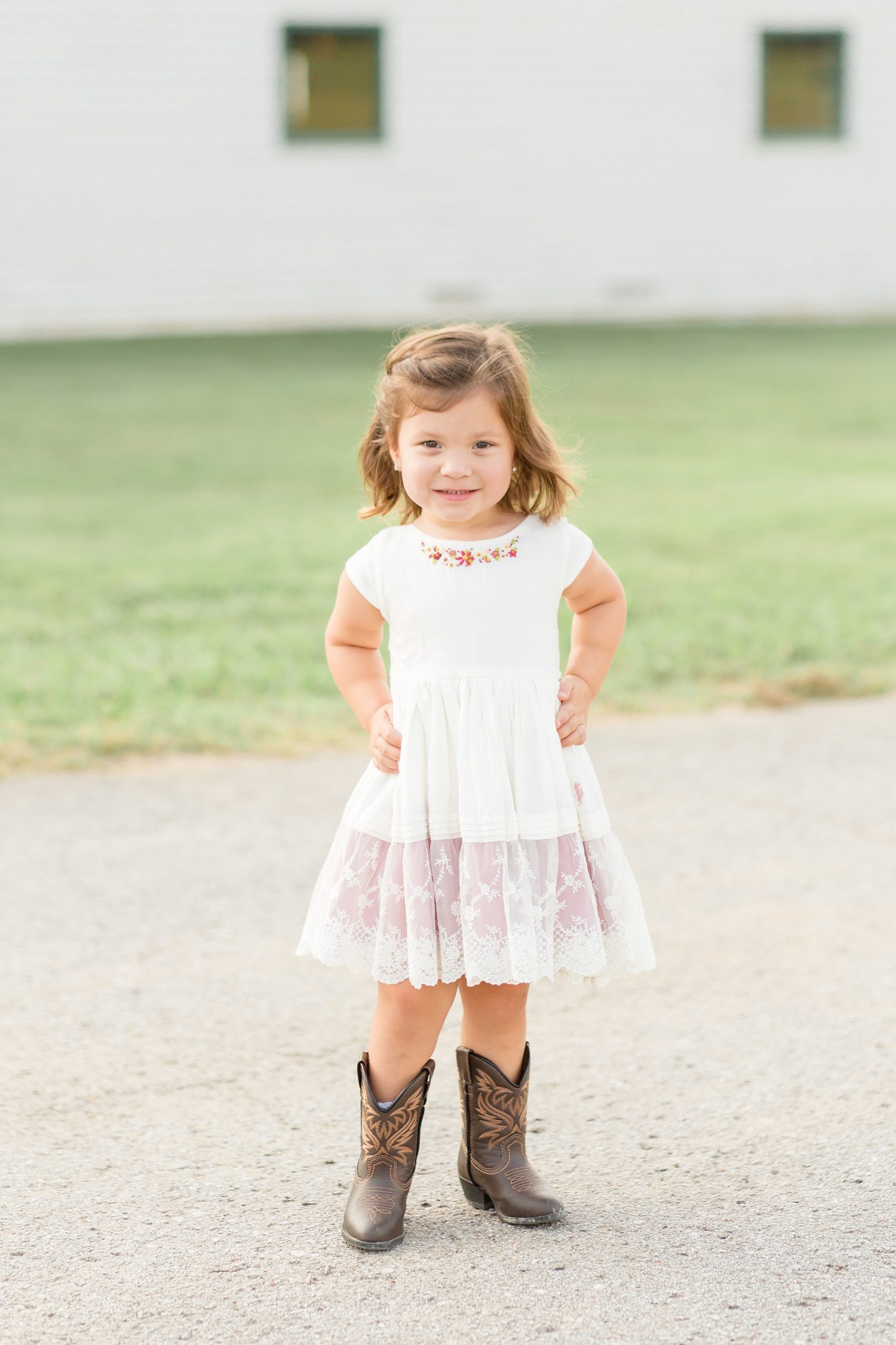toddler shows off white dress and cowboy boots