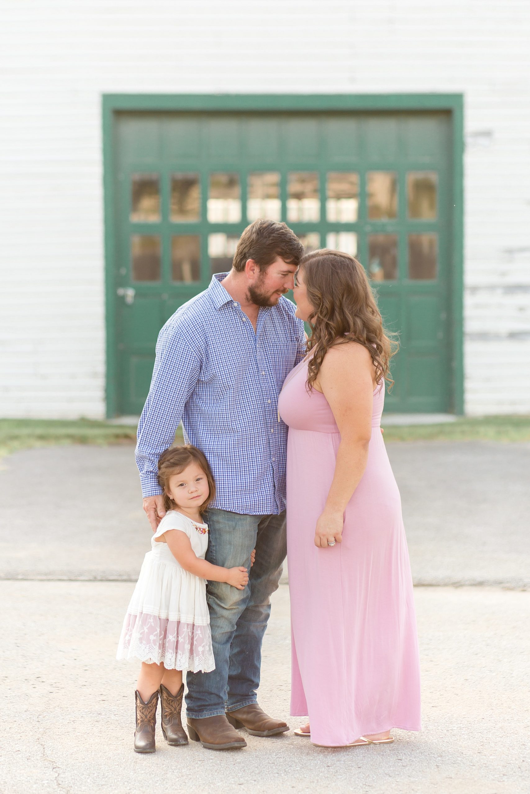mom in pink dress touches nose with husband in blue shirt during farm photos