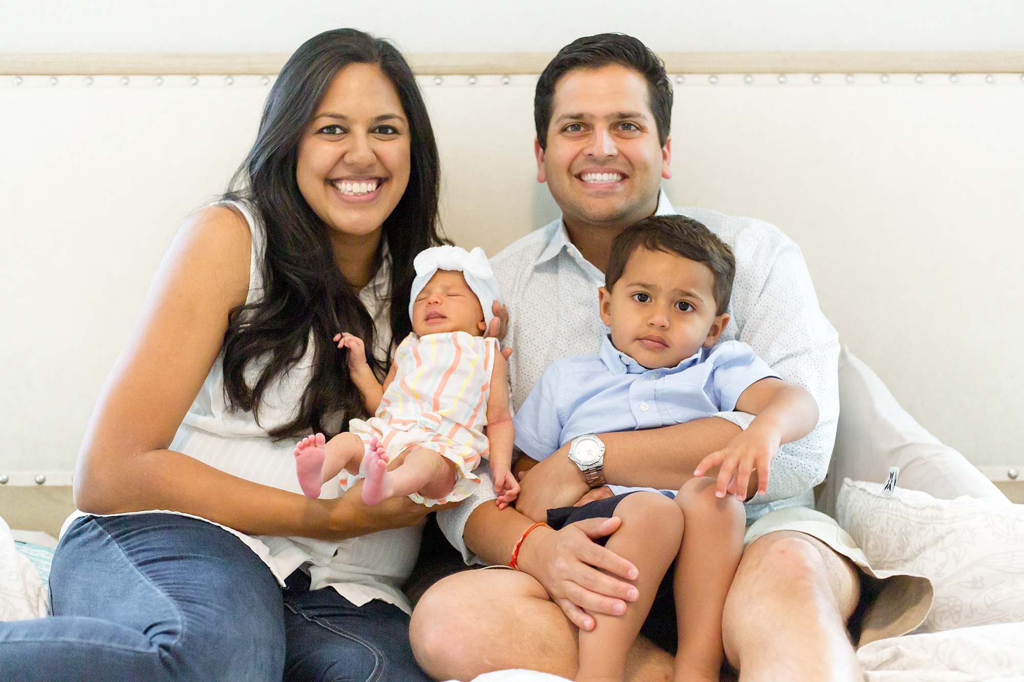 family of four smiles on bed during Lifestyle Newborn Session in Texas