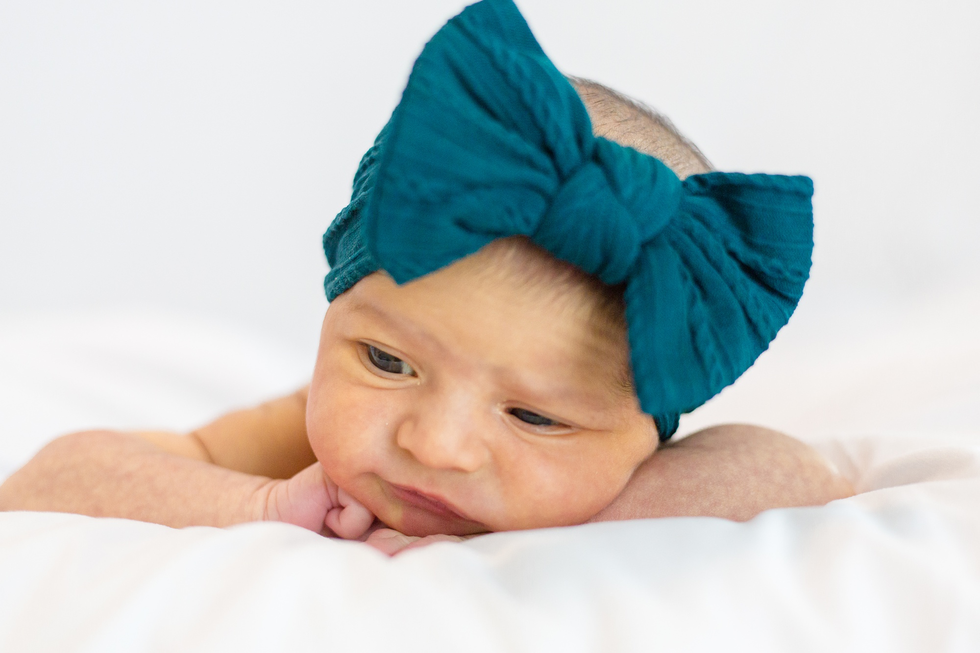 Lifestyle Newborn Session portraits of baby girl with teal bow
