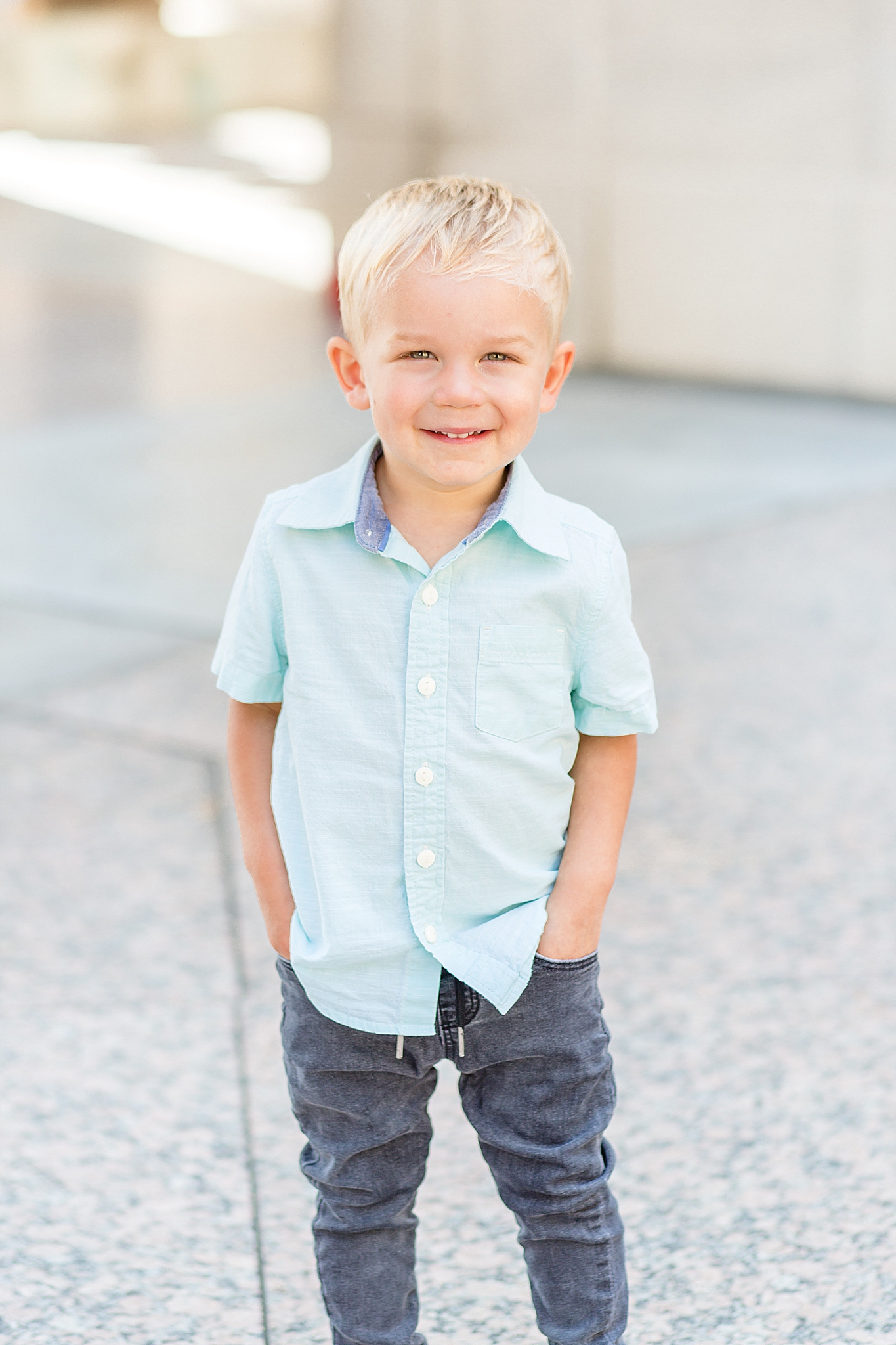 toddler poses with hands in pockets while wearing blue shirt