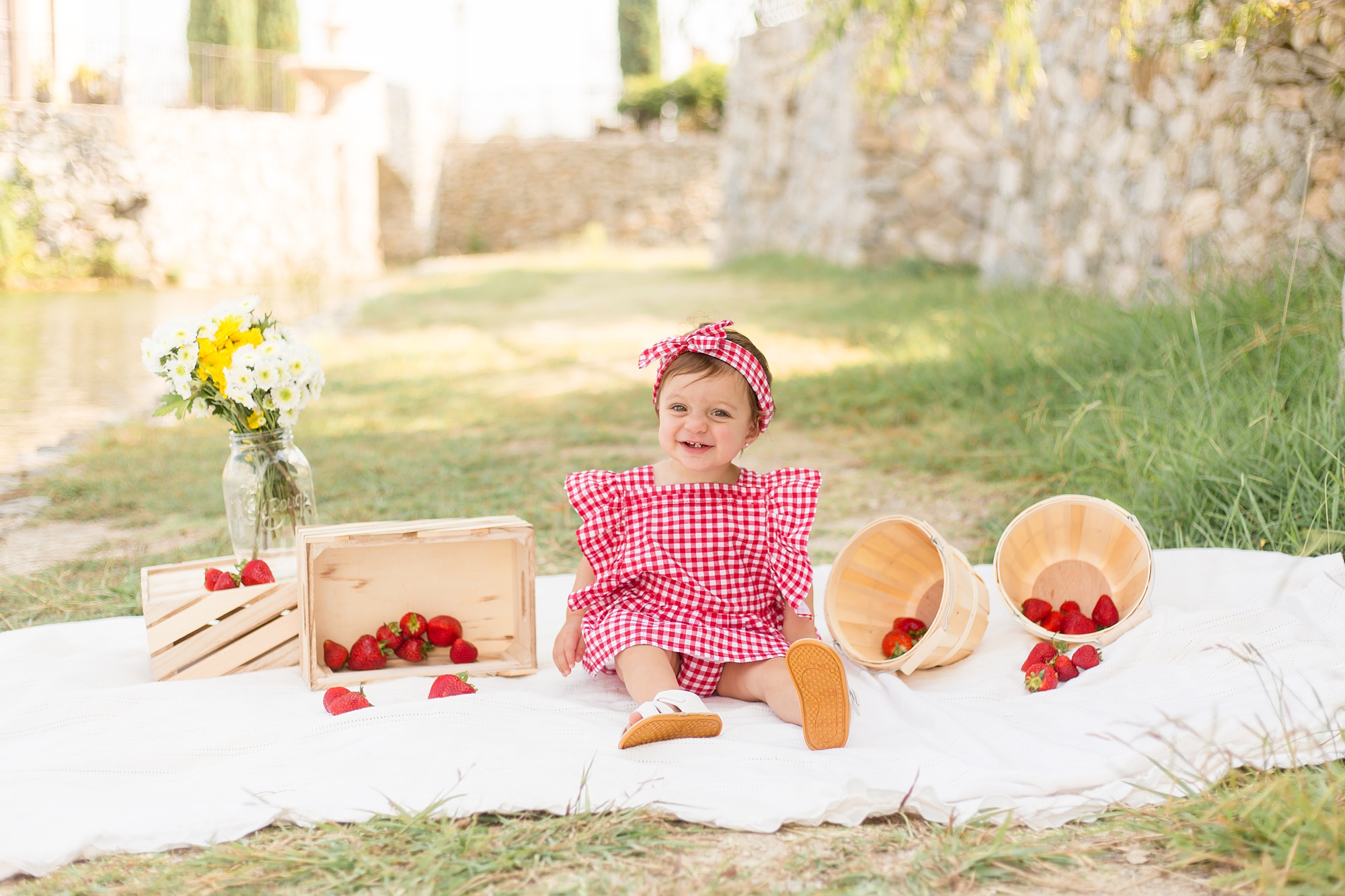 baby girl sits with strawberries in Adriatica Village for first birthday session