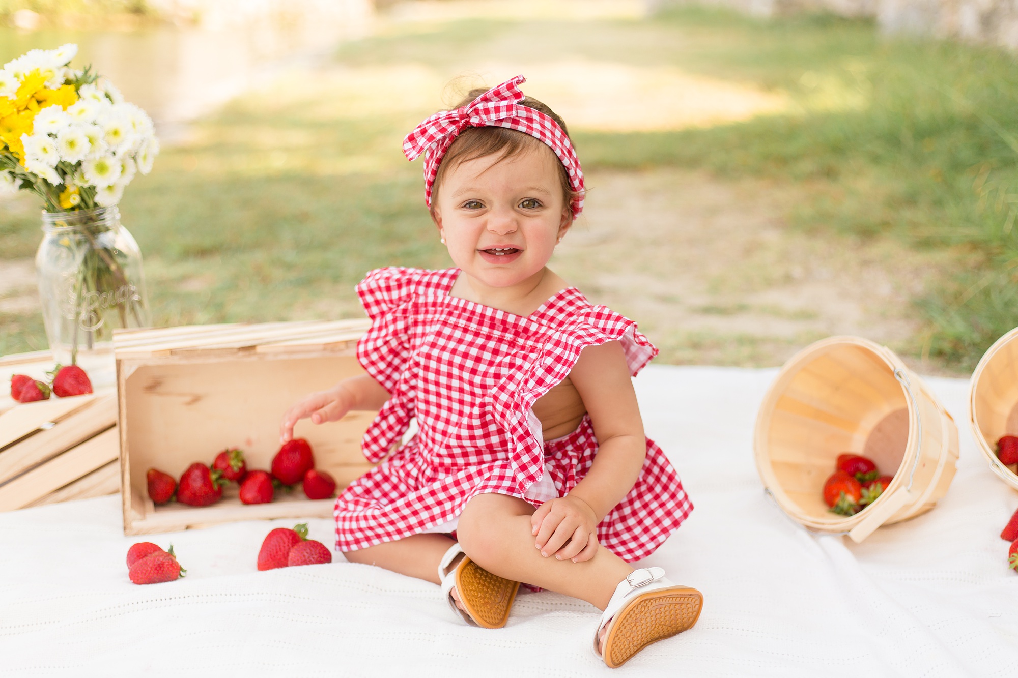 toddler girl sits in red checkered outfit for Adriatica Village 1st Birthday session