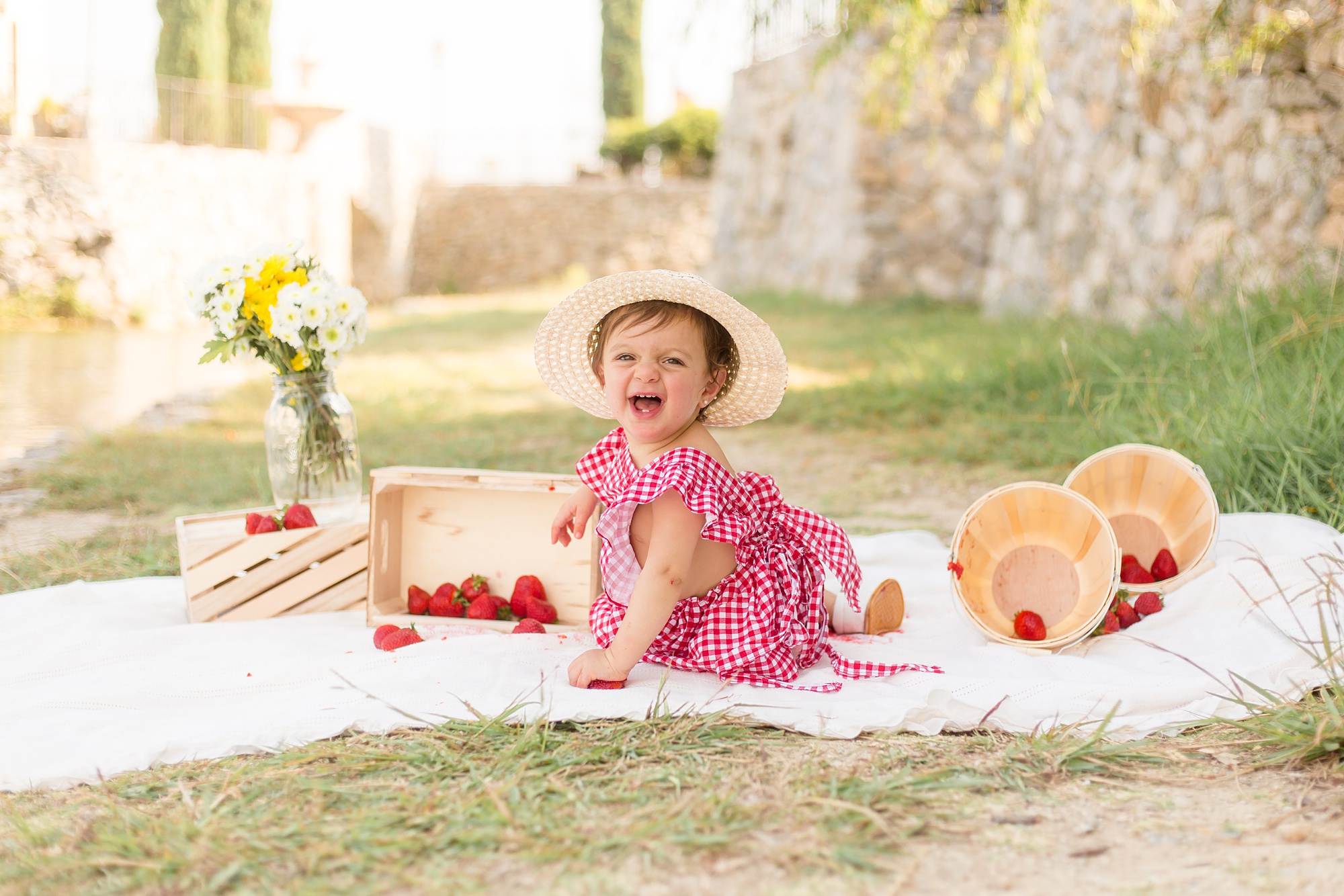 baby in straw hat laughs during Adriatica Village 1st Birthday photos