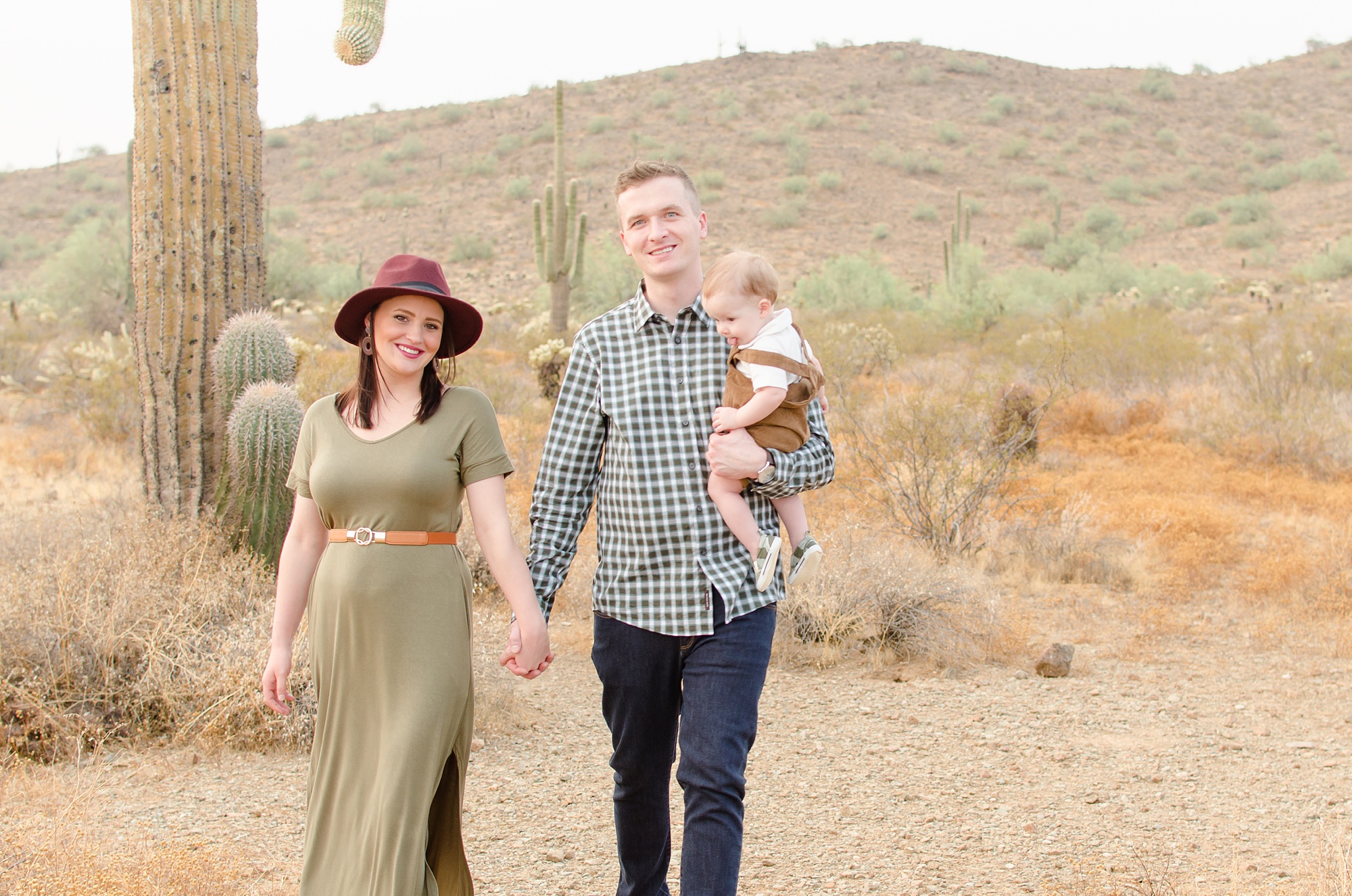 couple holds hands while walking with baby in Phoenix
