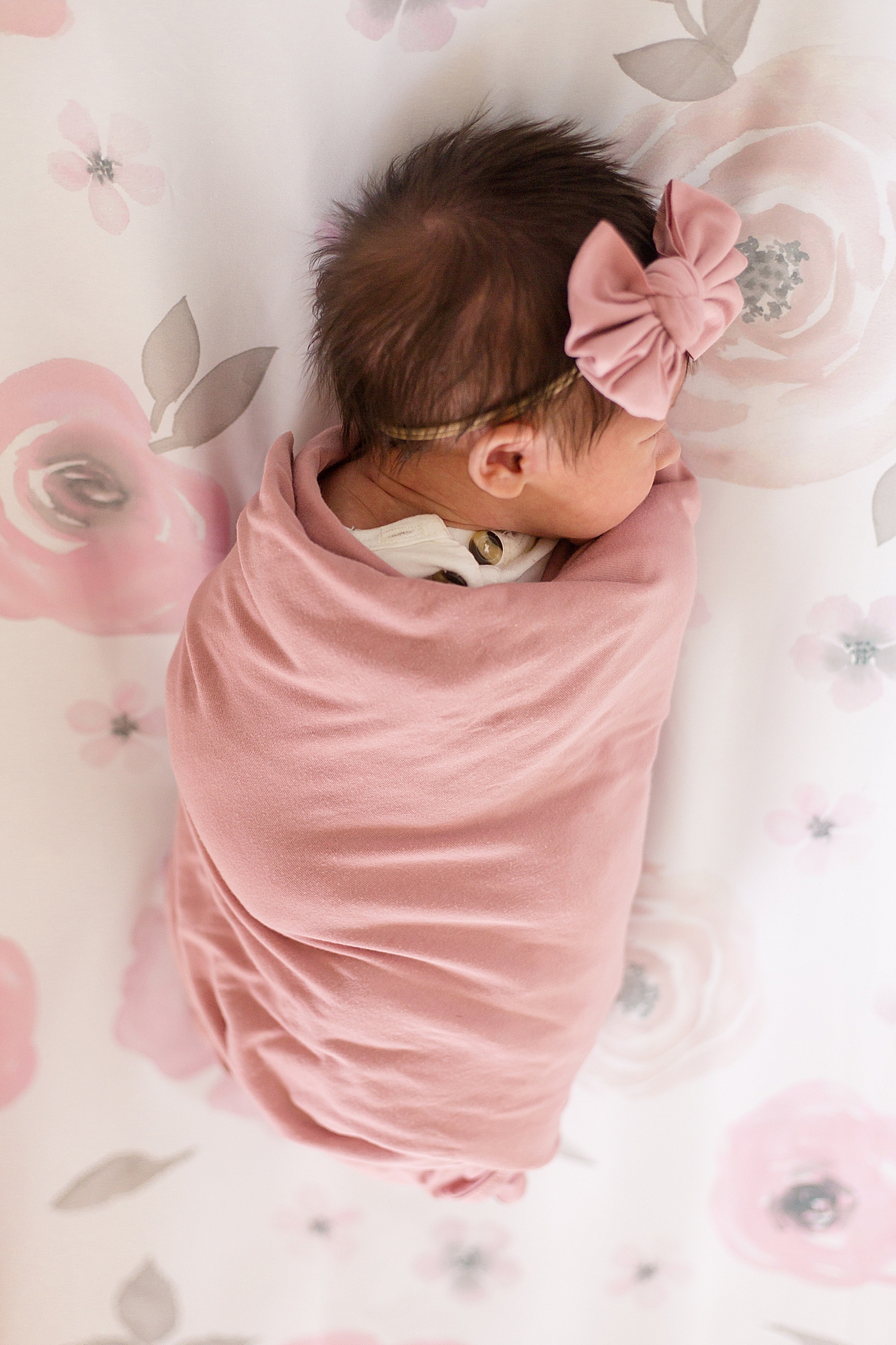 baby girl swaddled in light pink wrap