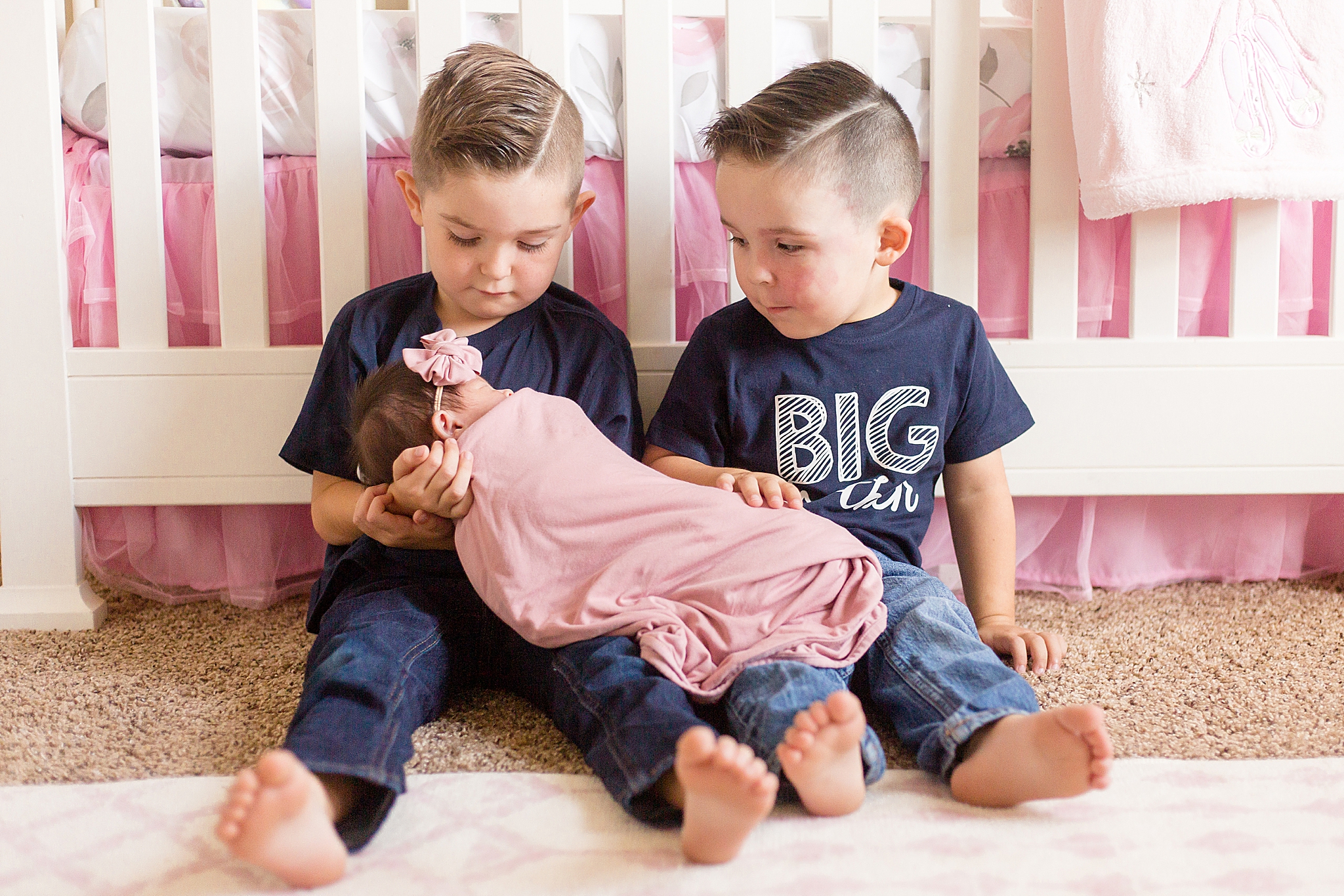 big brothers hold newborn baby girl during at home newborn portraits