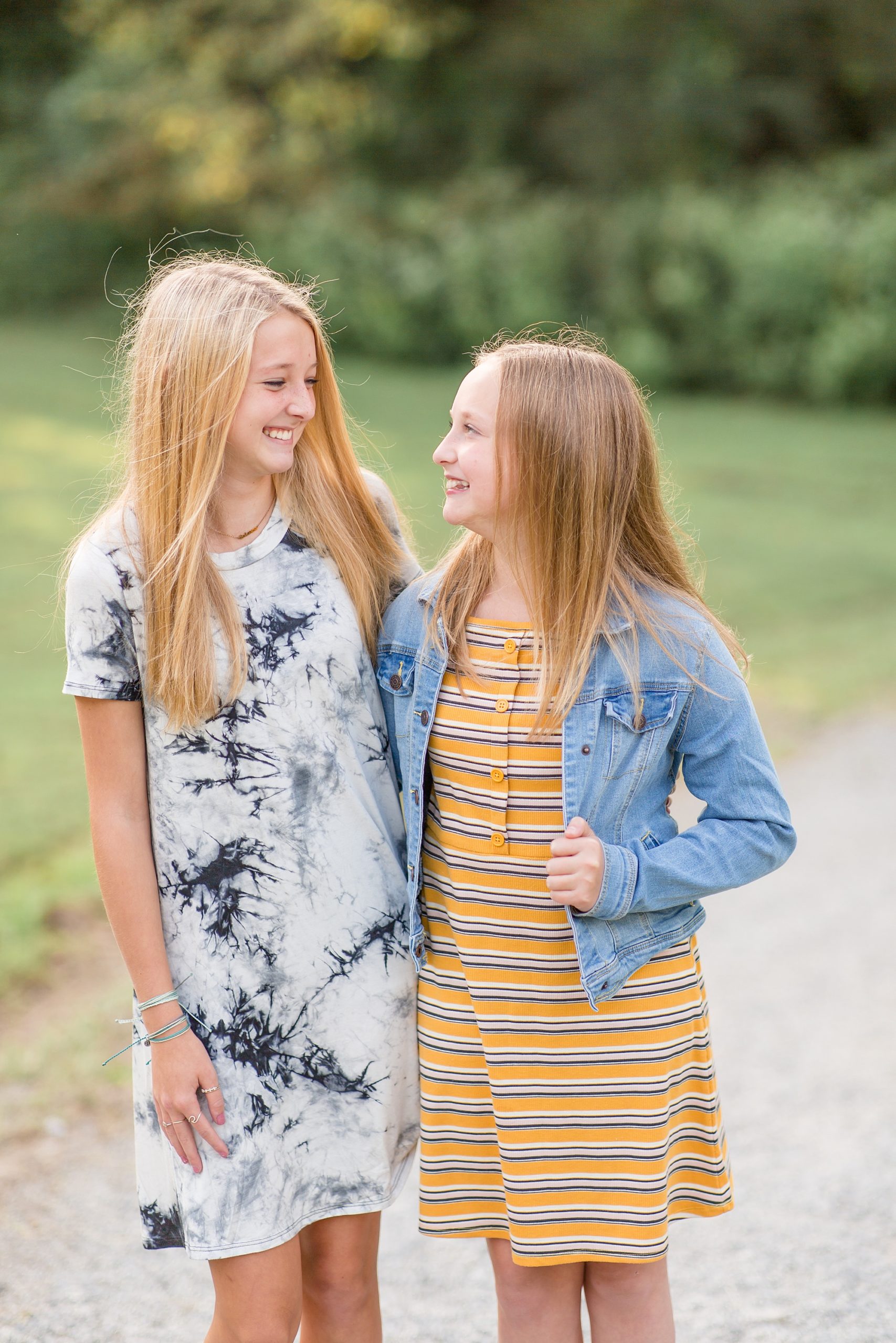 sisters smile at each other in blue and yellow dresses