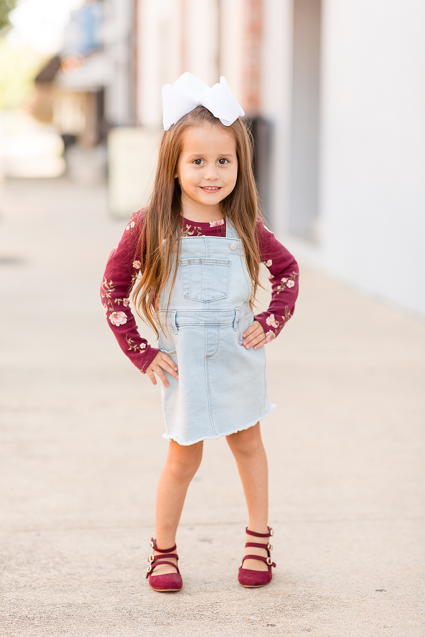 toddler in denim jumper poses in Downtown McKinney Square