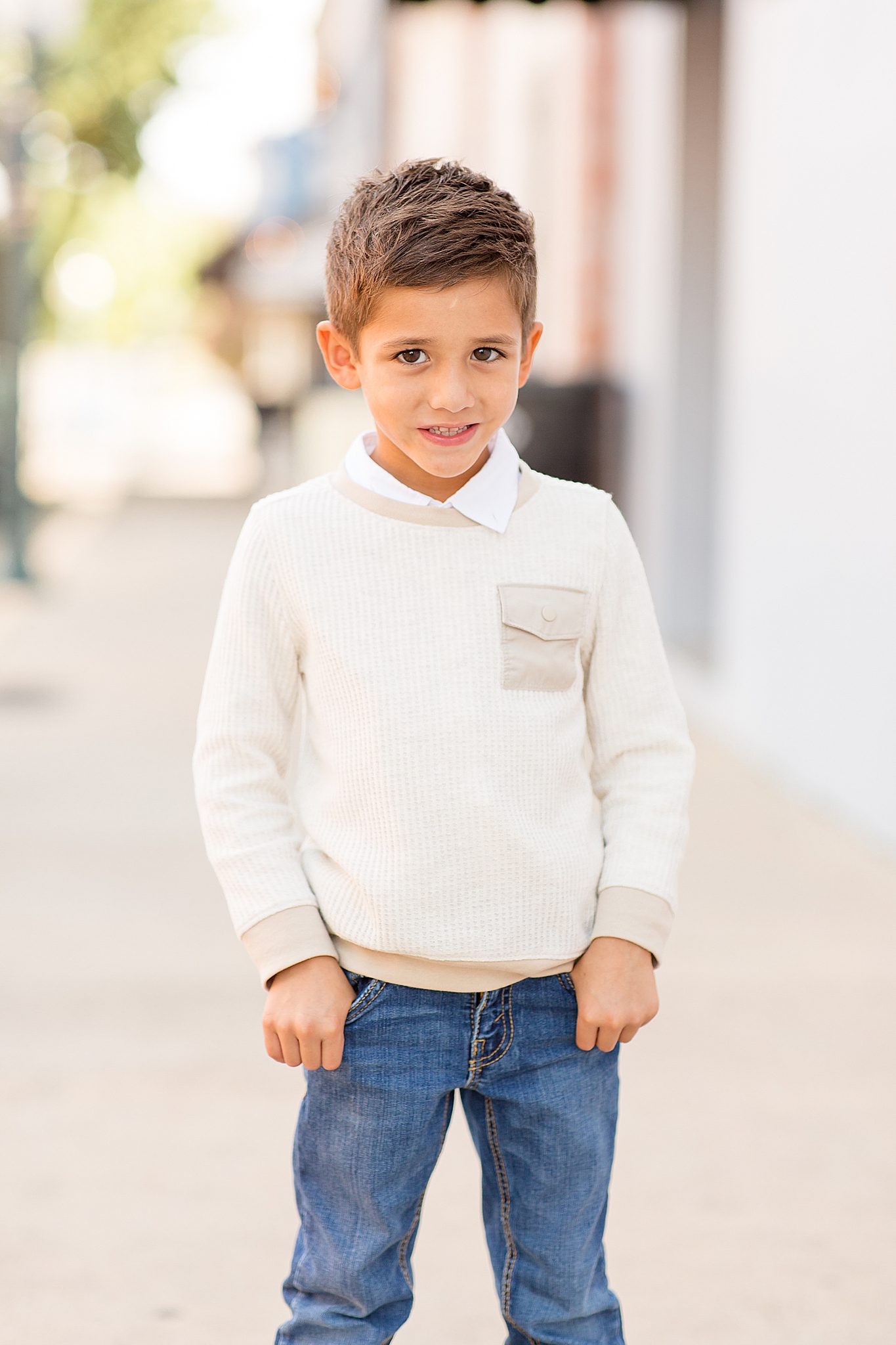 toddler boy in ivory sweater smiles during Downtown McKinney Square Fall Minis