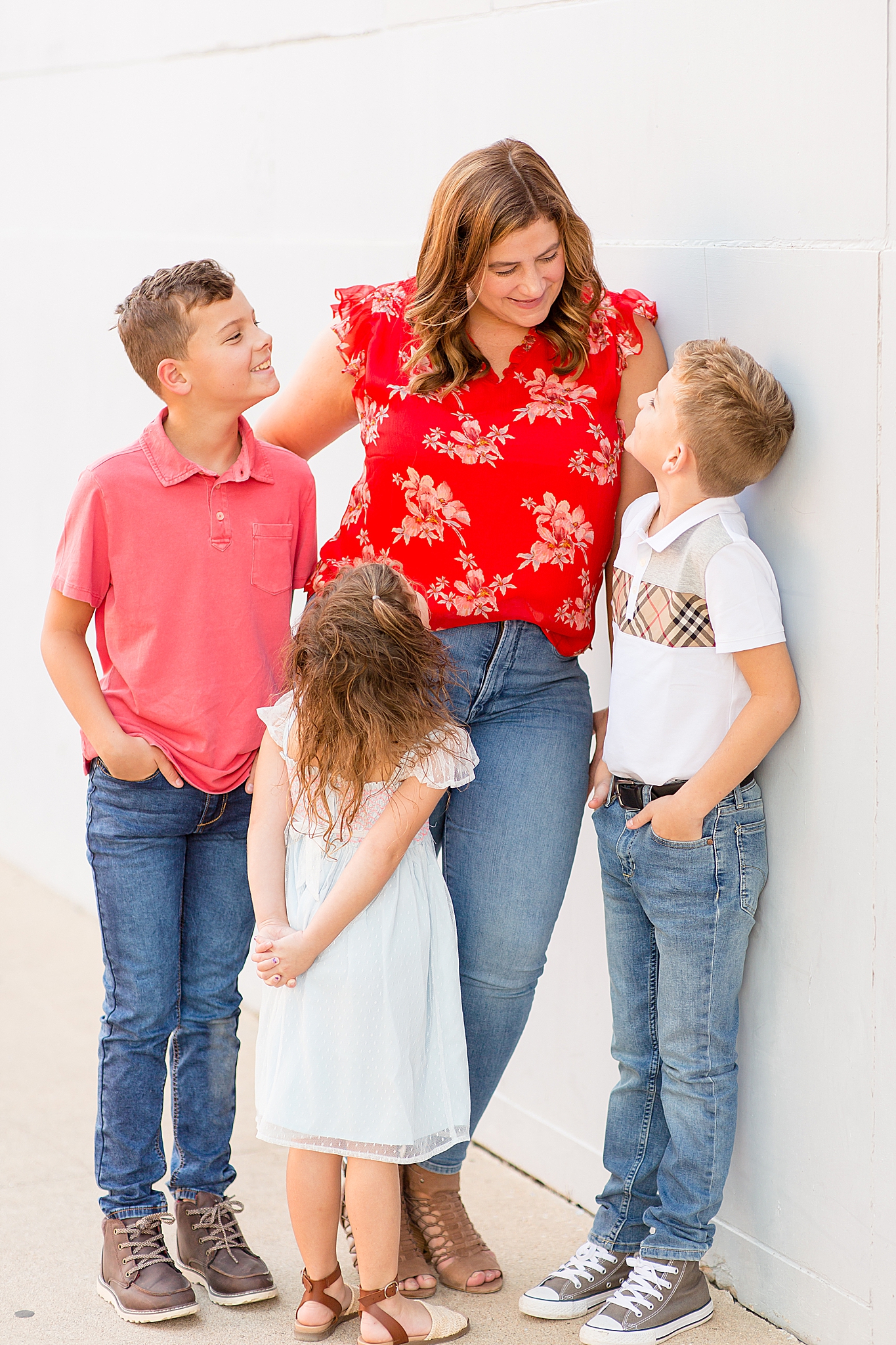 three kids look at mom in red shirt during Texas family portraits