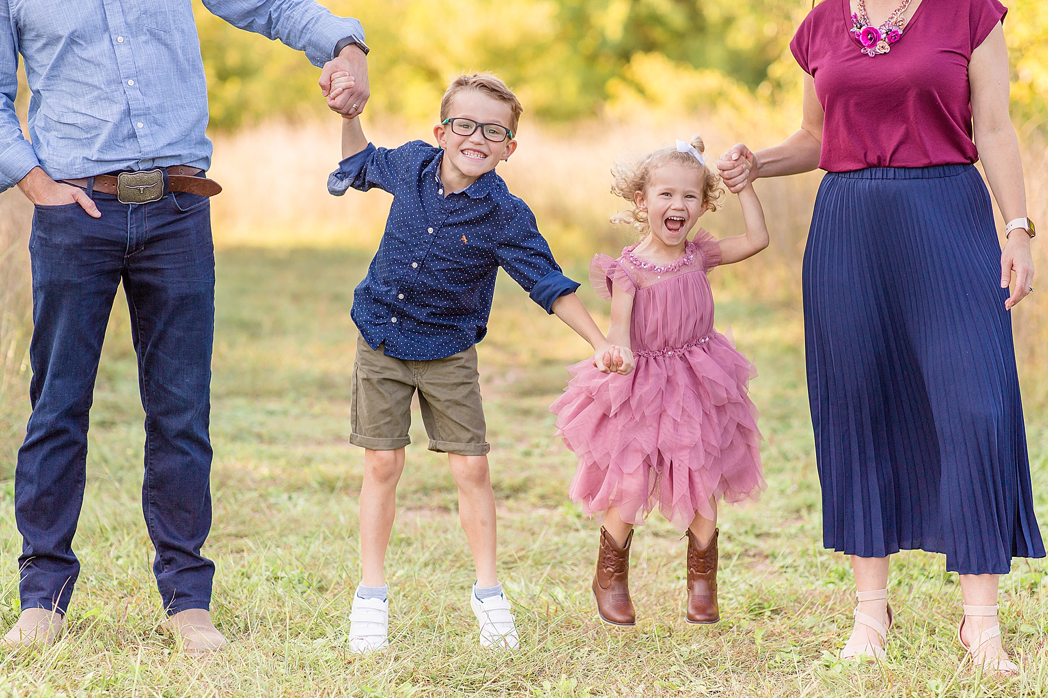 children jump while holding parents' hands during Frisco Commons Fall Minis