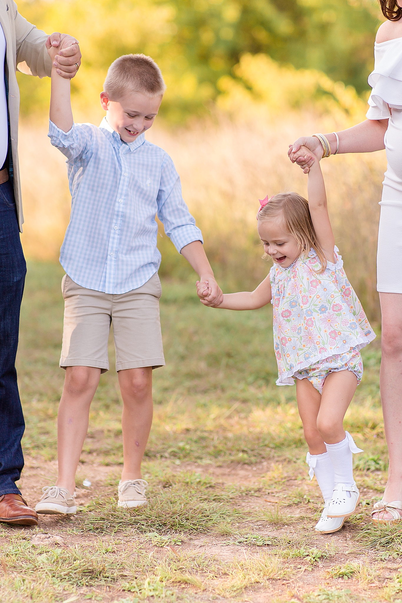 siblings hold hands and play during family photos