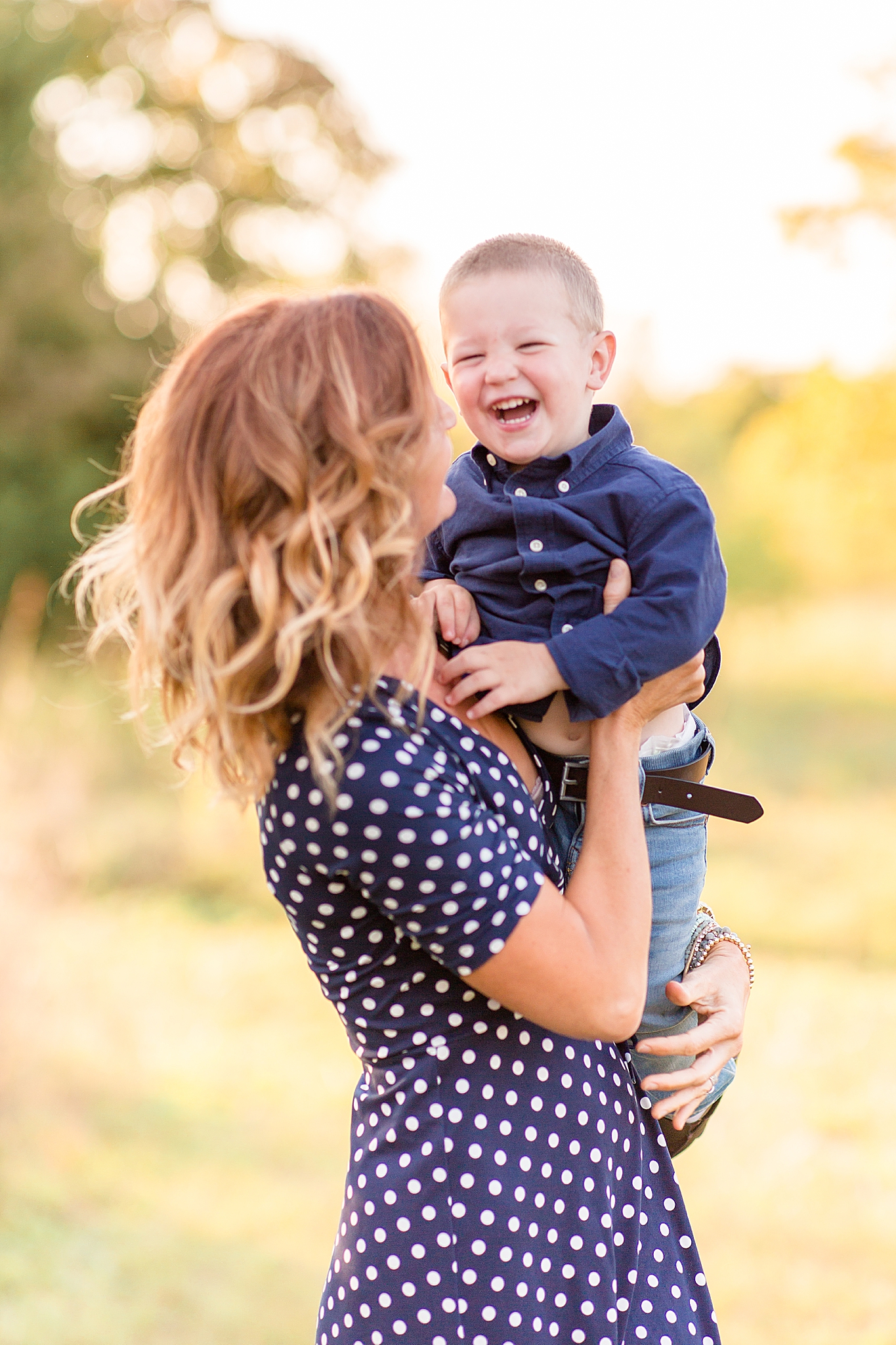 son laughs while mom picks him up during Frisco Commons Fall Minis