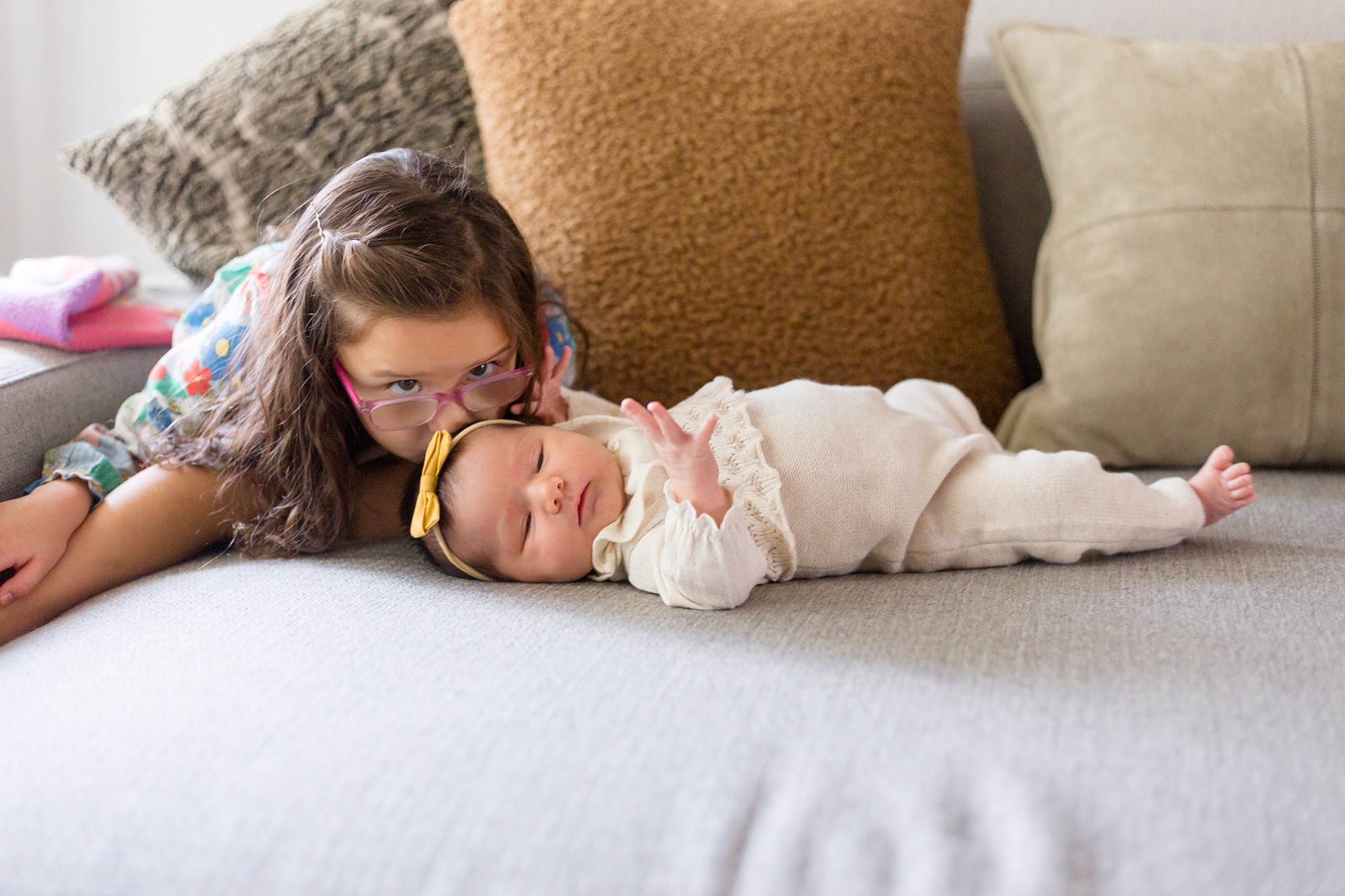 big sister kisses baby during newborn session at home