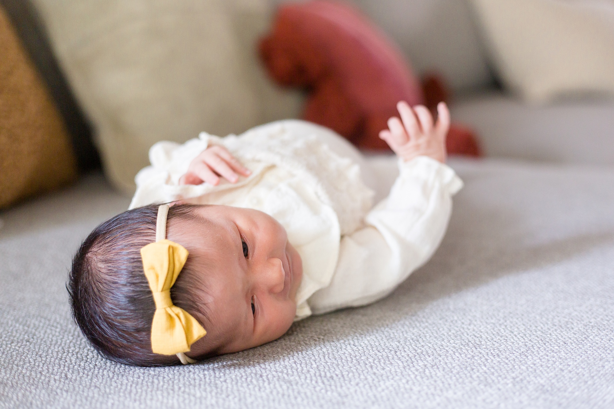 baby lays on couch during newborn portraits at home