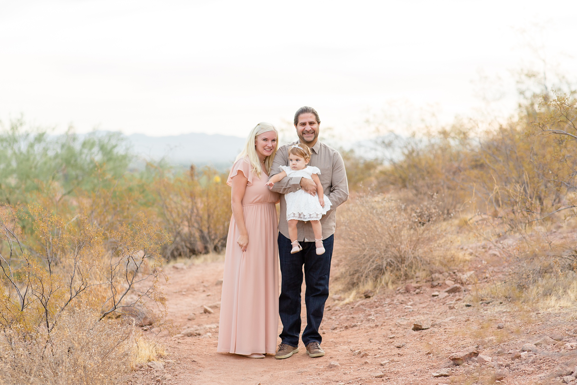 parents hold toddler girl during desert family photos
