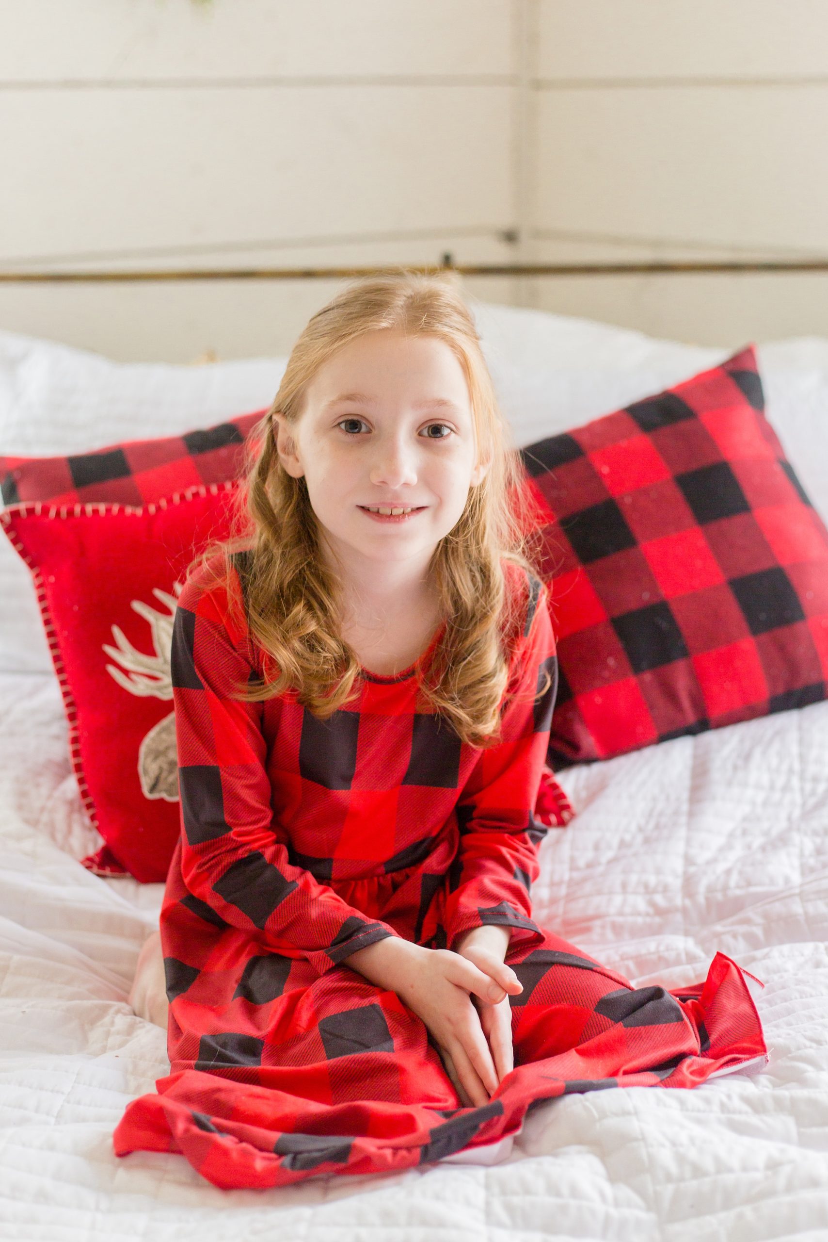 daughter in plaid PJs sits on bed during Studio House Christmas Minis in Texas
