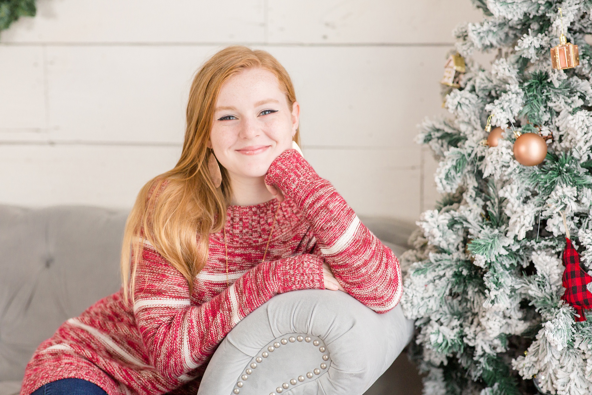 teenager poses on couch by Christmas tree