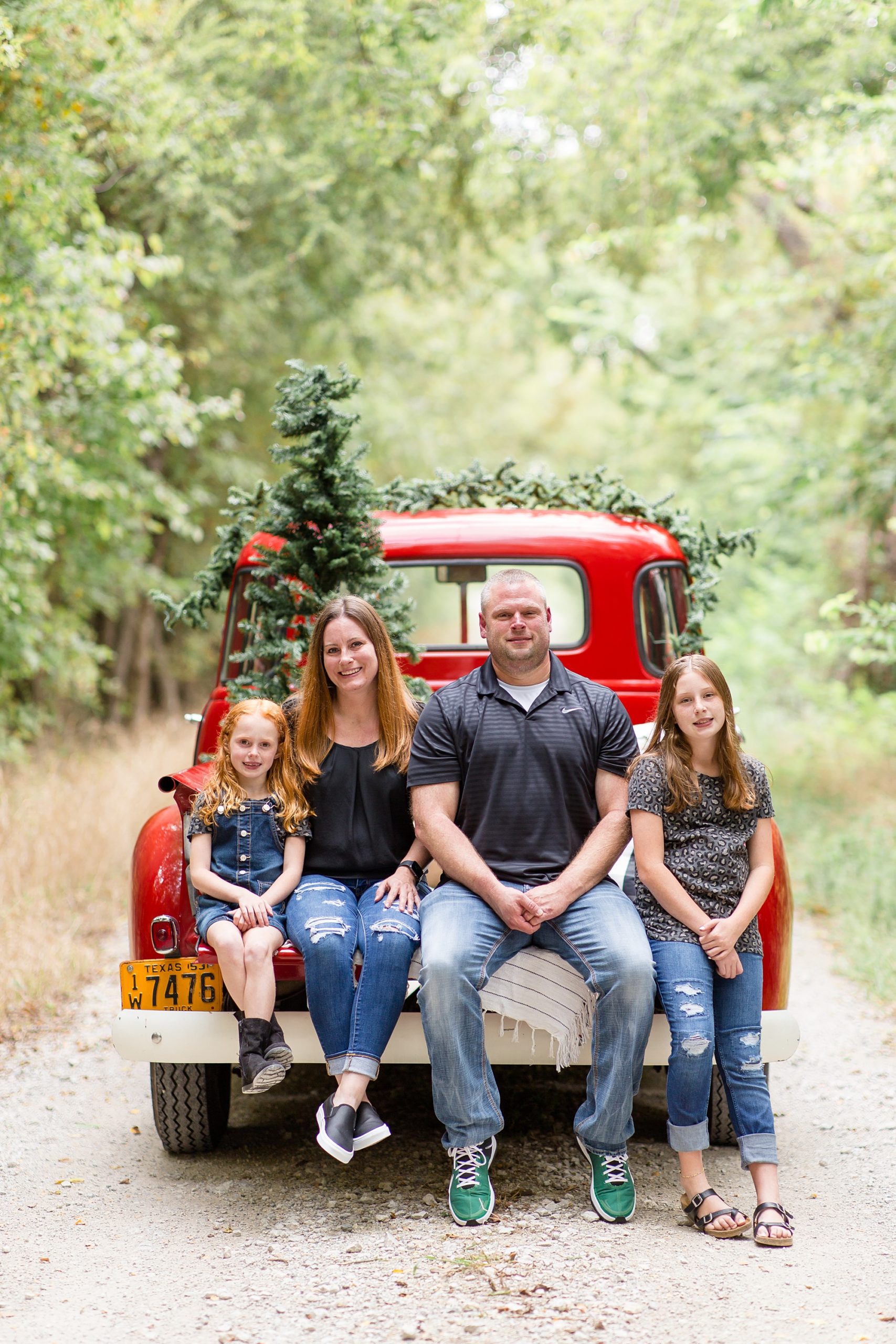 family of four poses on bed of Red Truck
