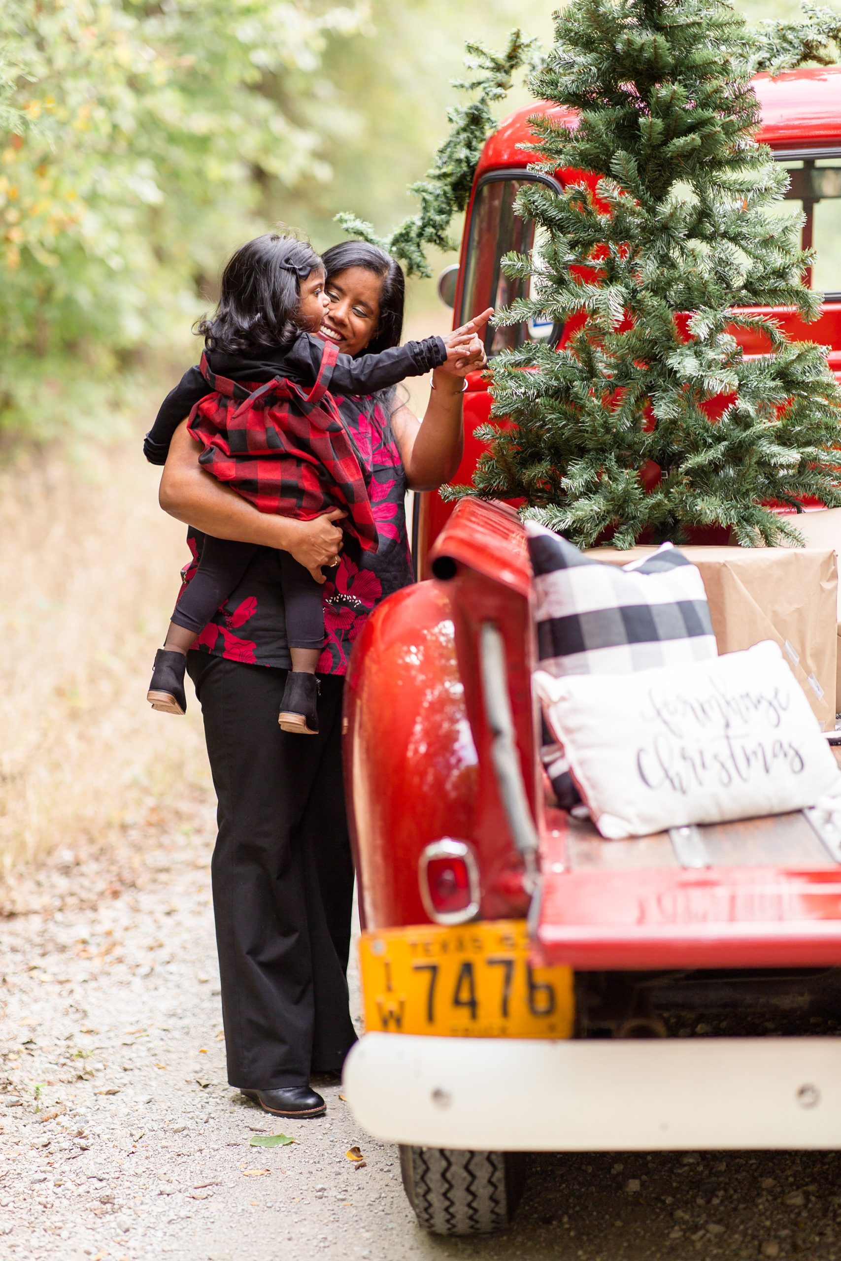 mom shows daughter Christmas tree during Red Truck Christmas minis