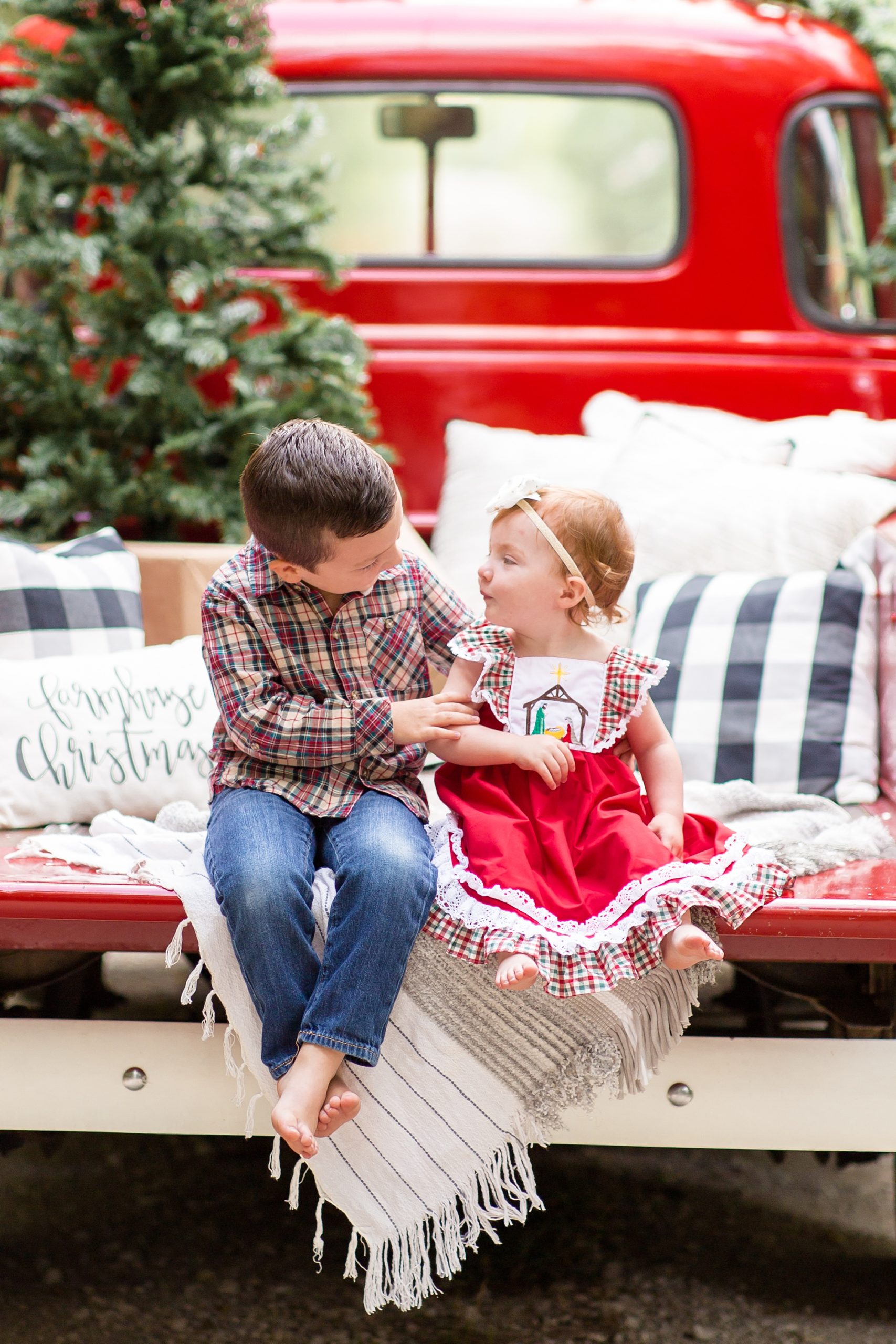 siblings sit on bed of truck during holiday mini session