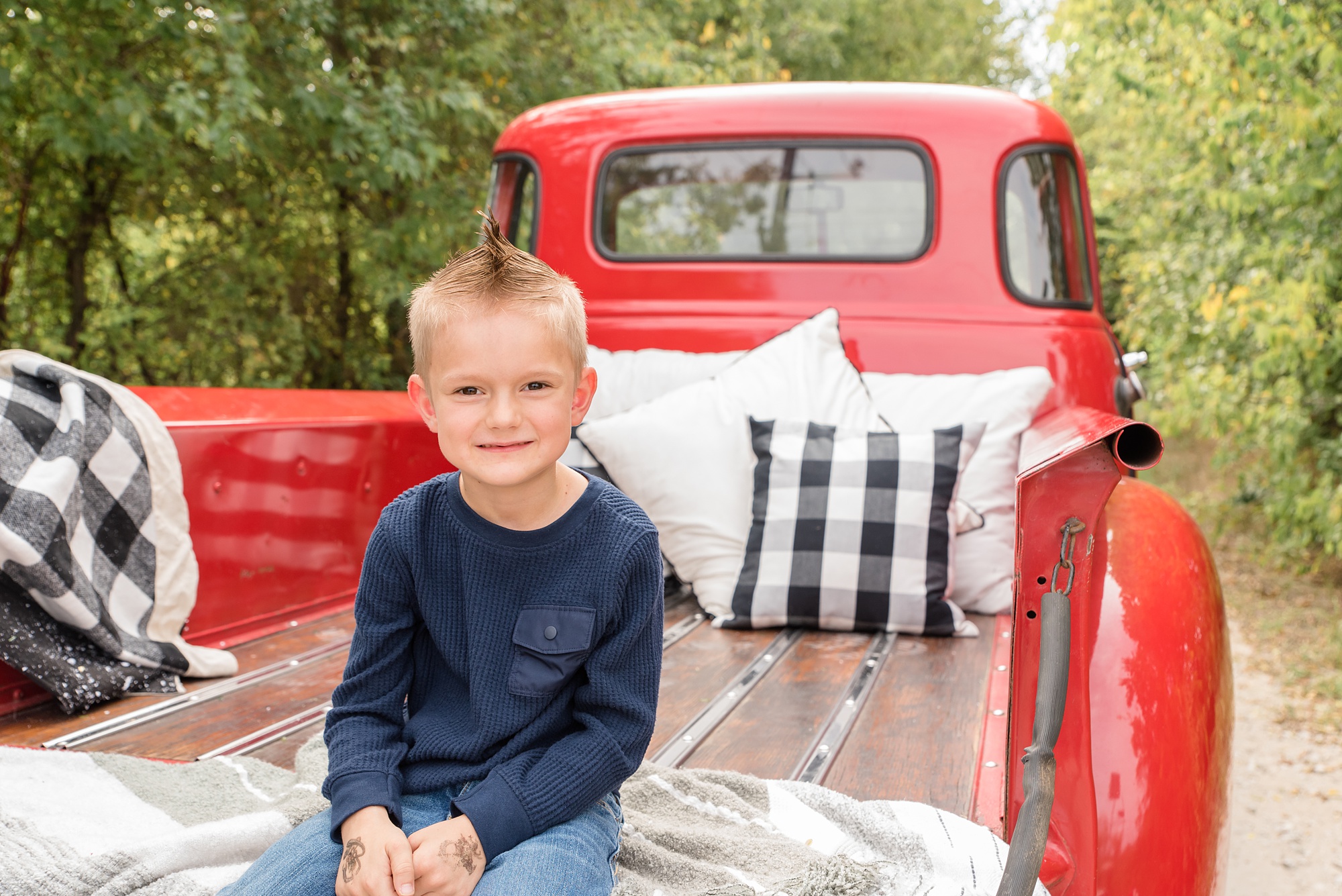 son sits on bed of truck with farmhouse decor