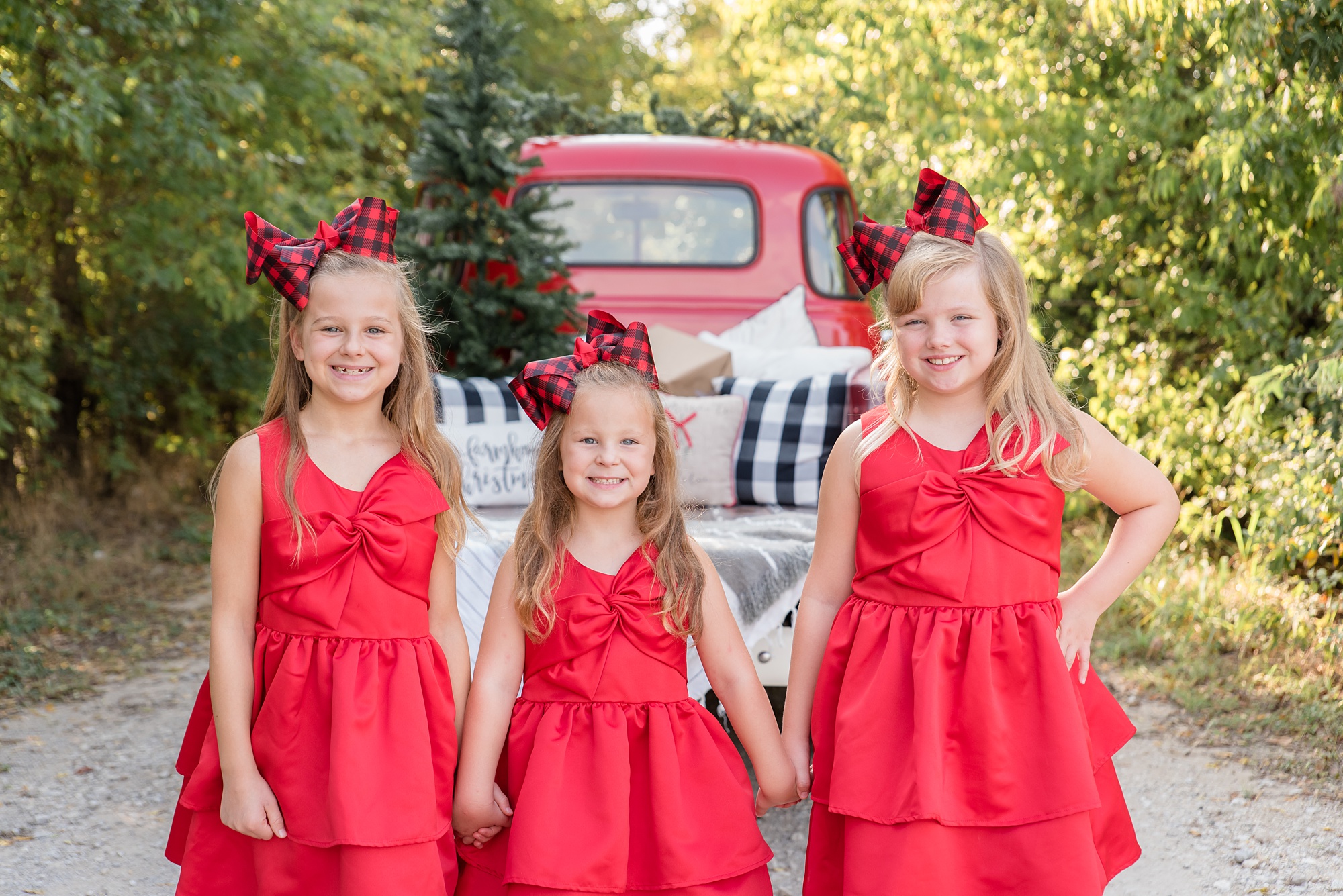 sisters in matching red dresses hold hands by truck