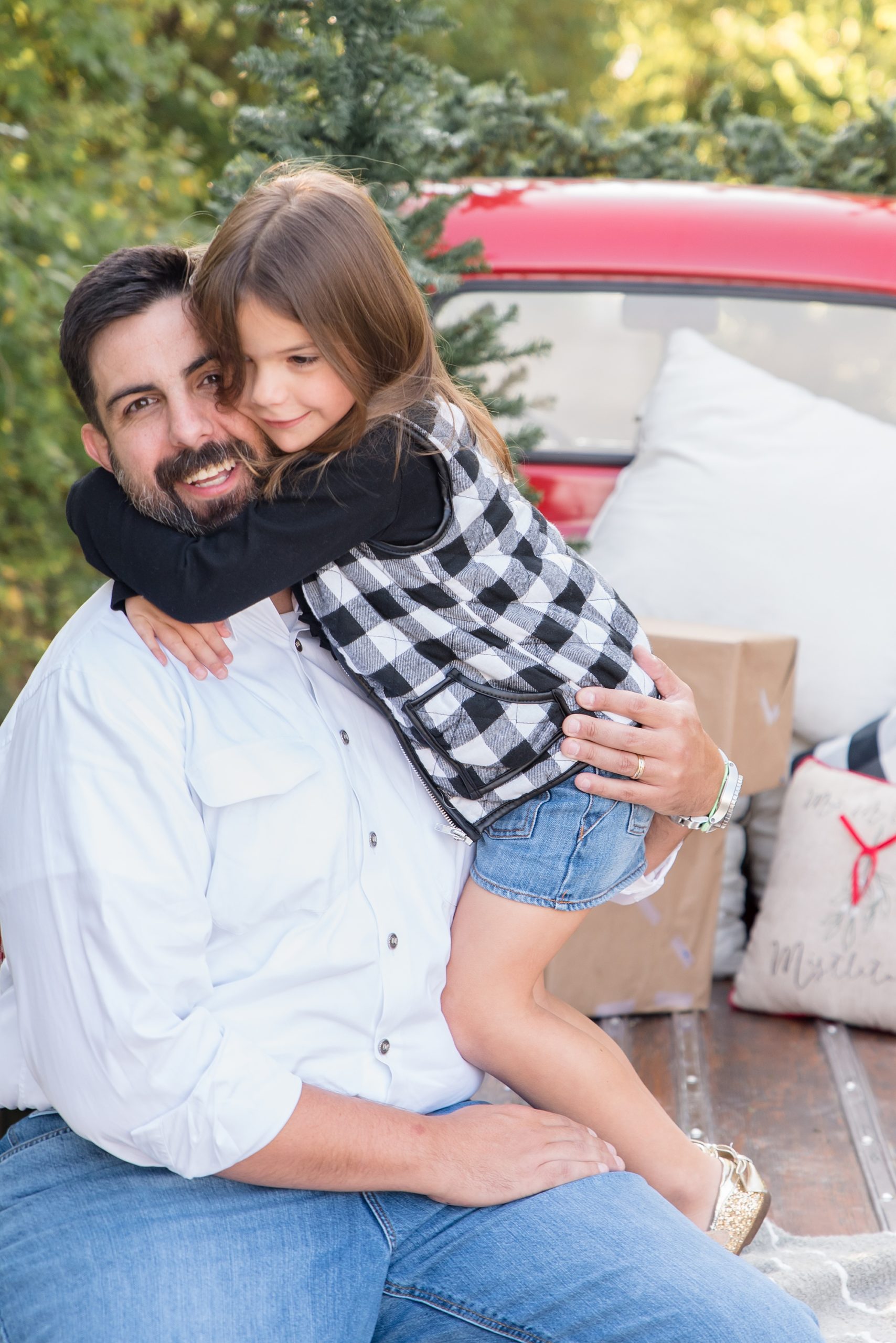 daughter hugs dad during Red Truck Christmas minis