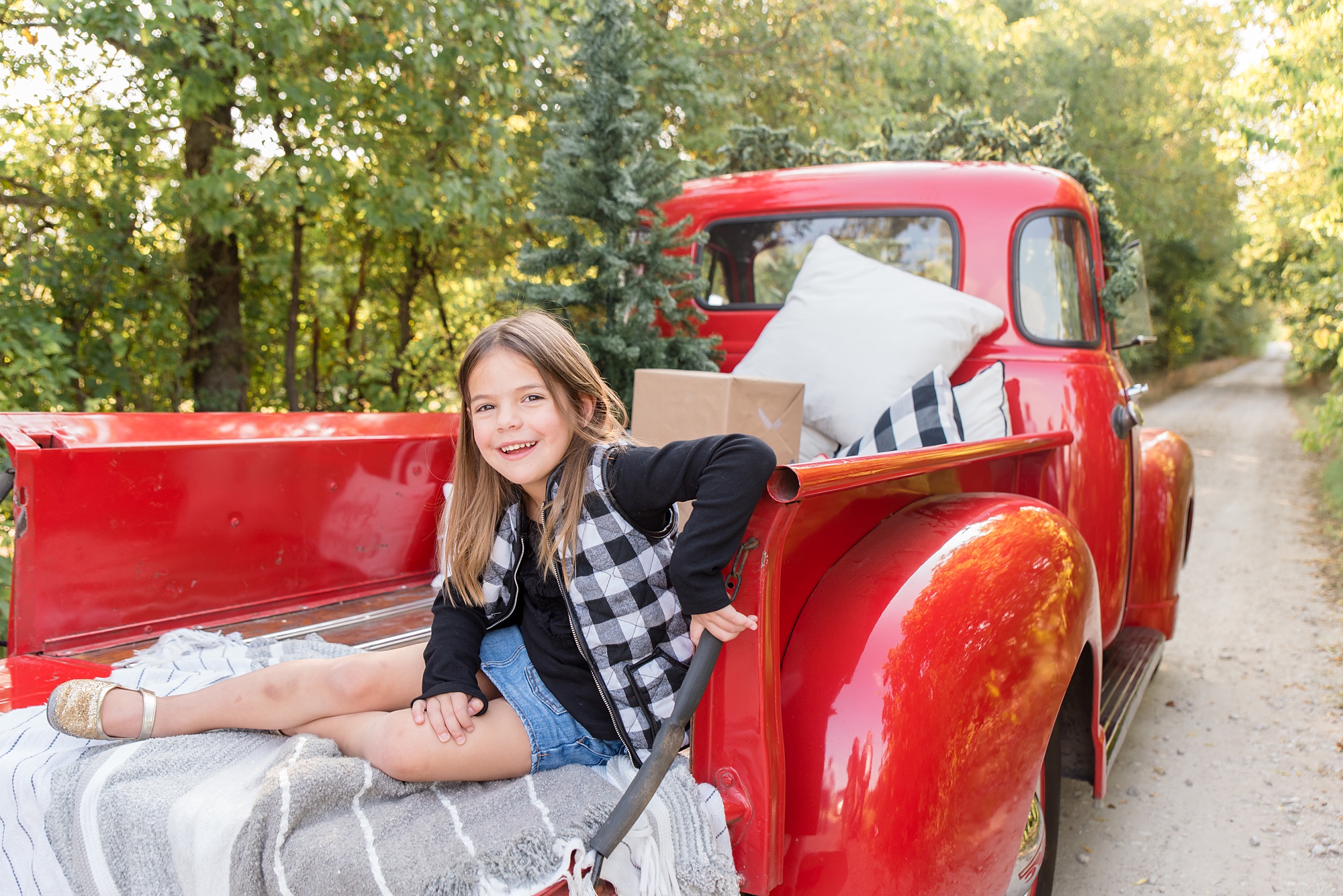 young girl sits in back of red truck