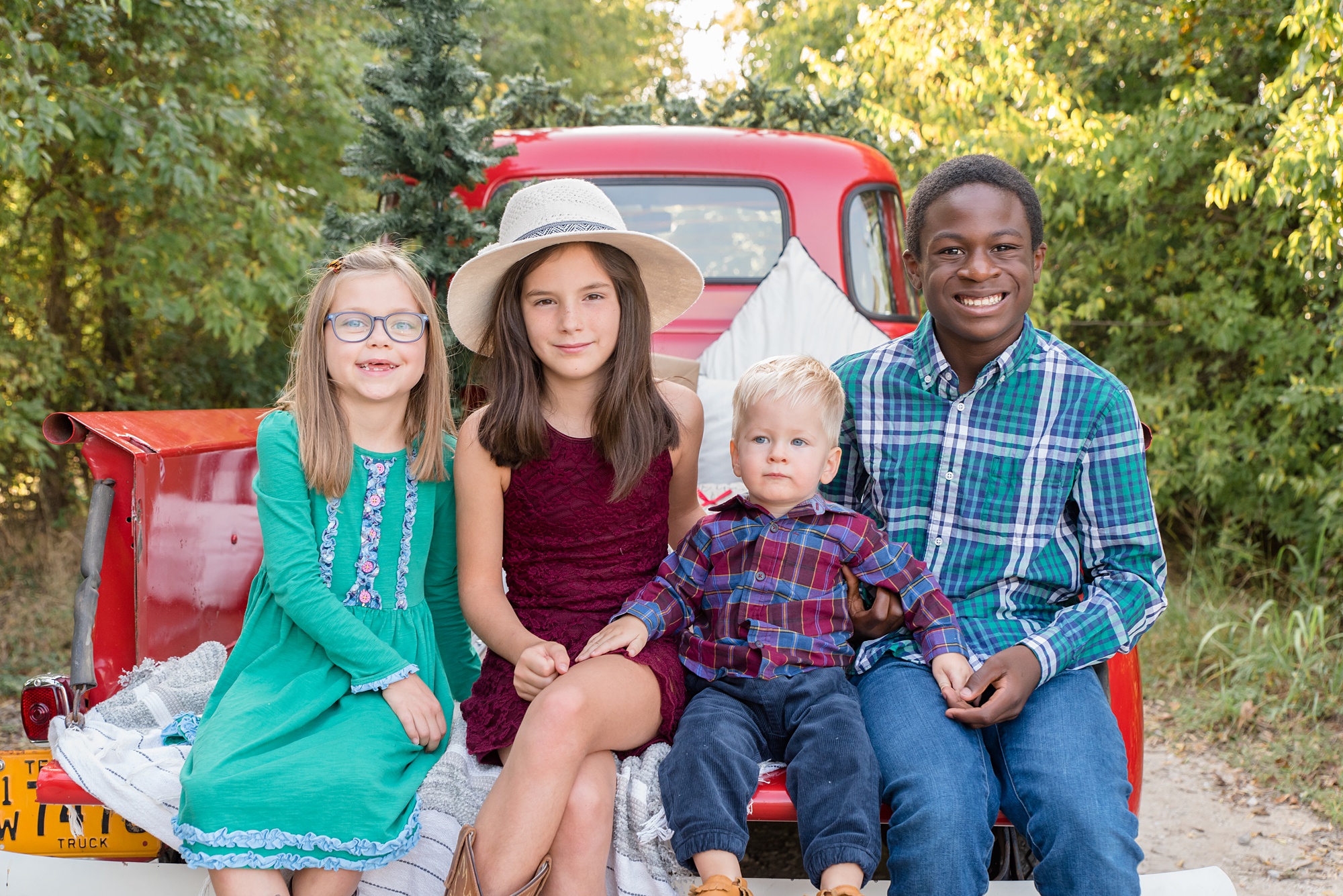 four siblings sit on bed of truck