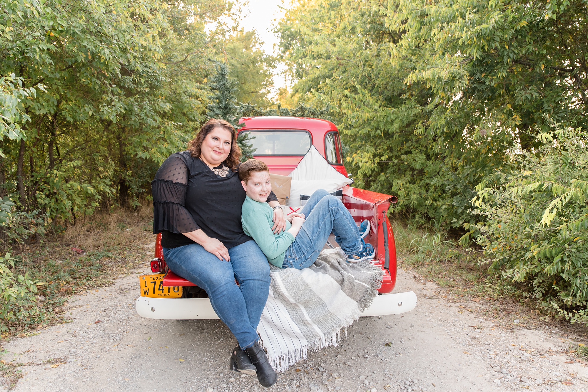 mom and son sit on vintage red truck