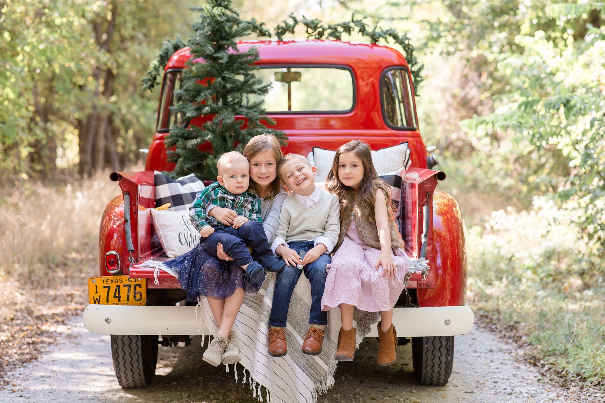 siblings sit on back of truck during Red Truck Christmas minis