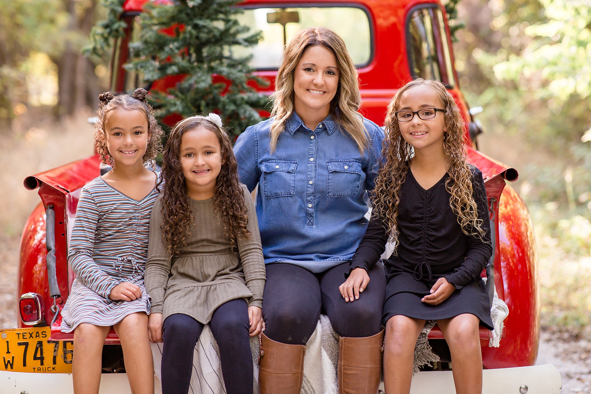 mom sits with three daughters during Red Truck Christmas minis