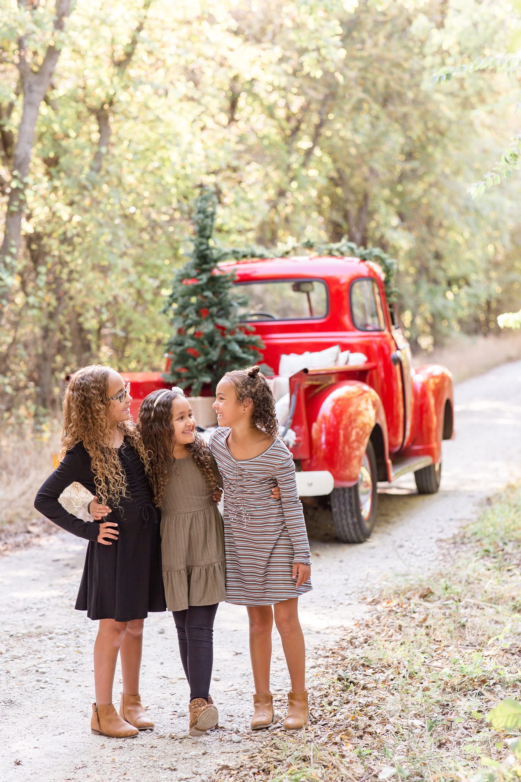 three girls pose next to red truck