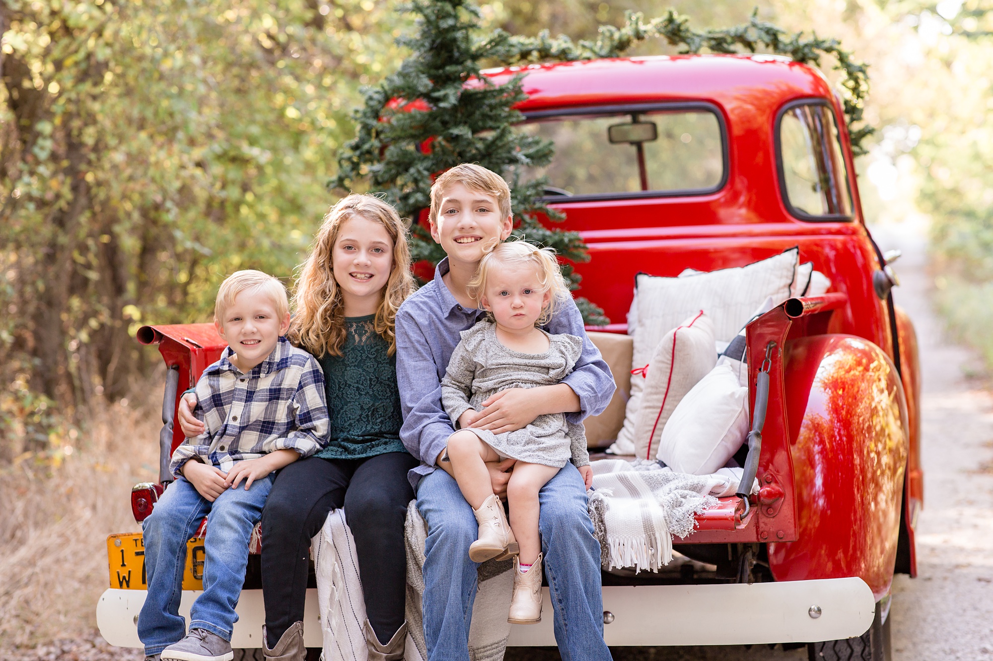 family poses on back of truck during Red Truck Christmas minis
