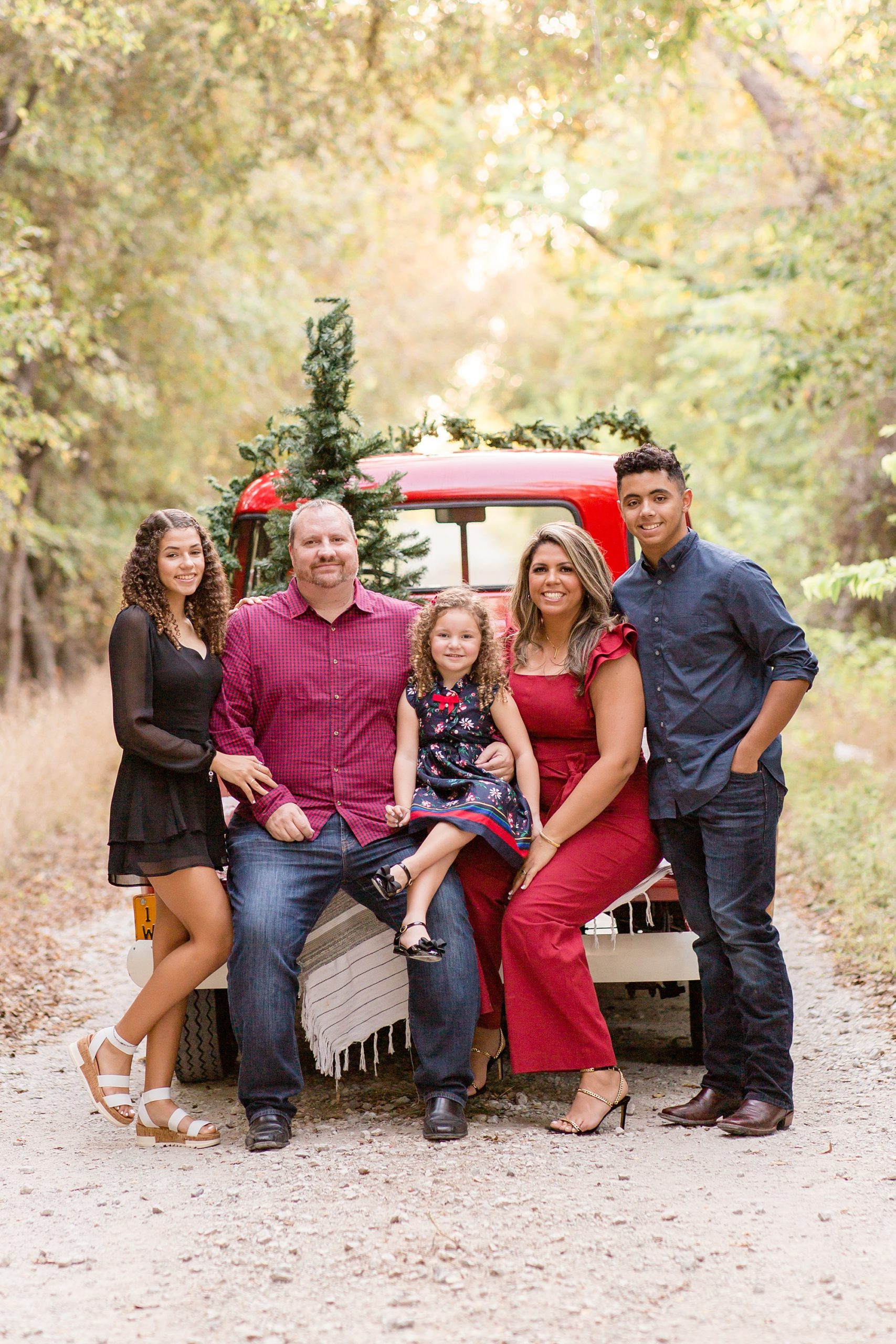 family sits on back of red truck during McKinney TX mini sessions