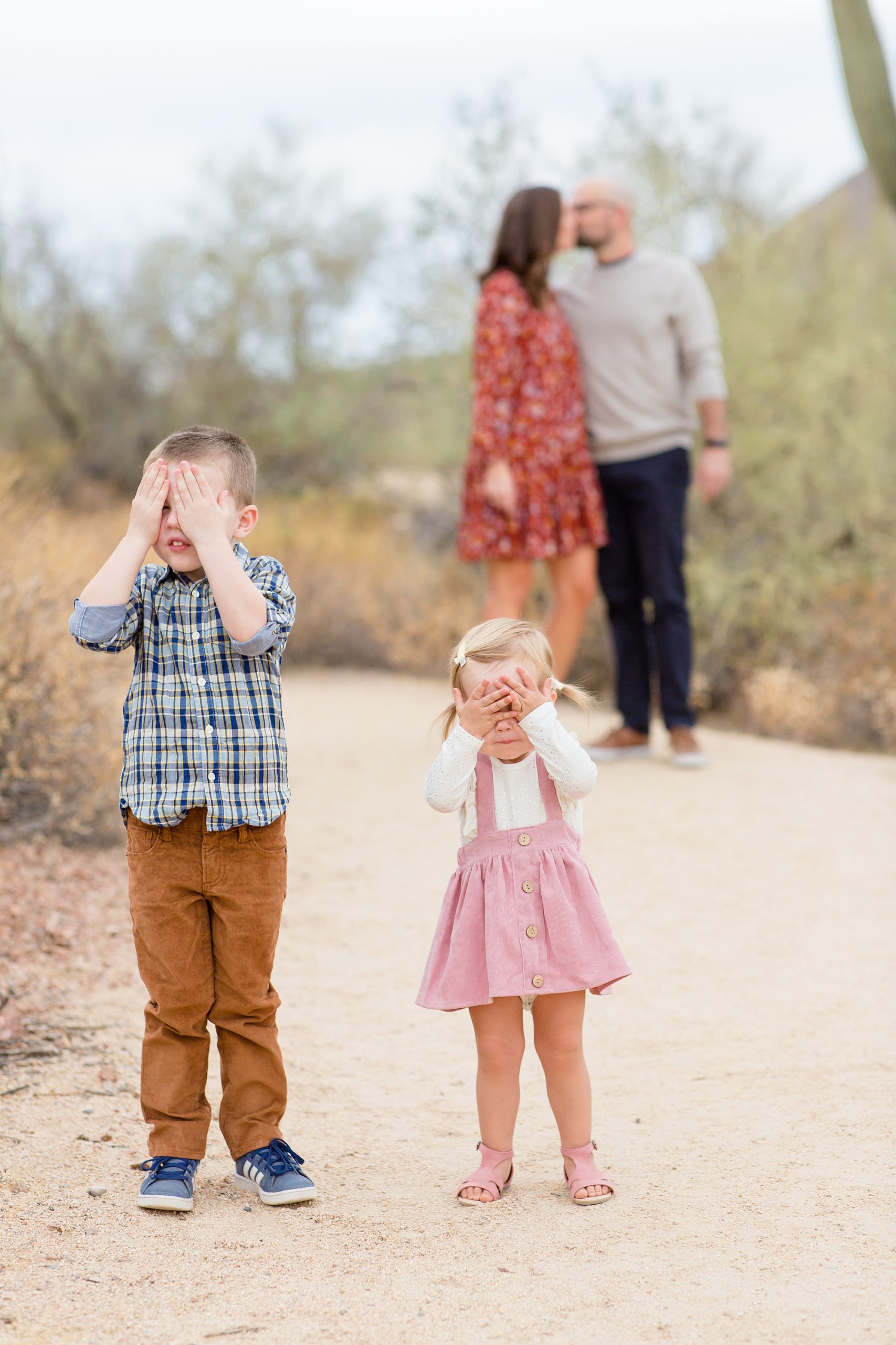 kids cover eyes while mom and dad kiss during Usery Park fall minis