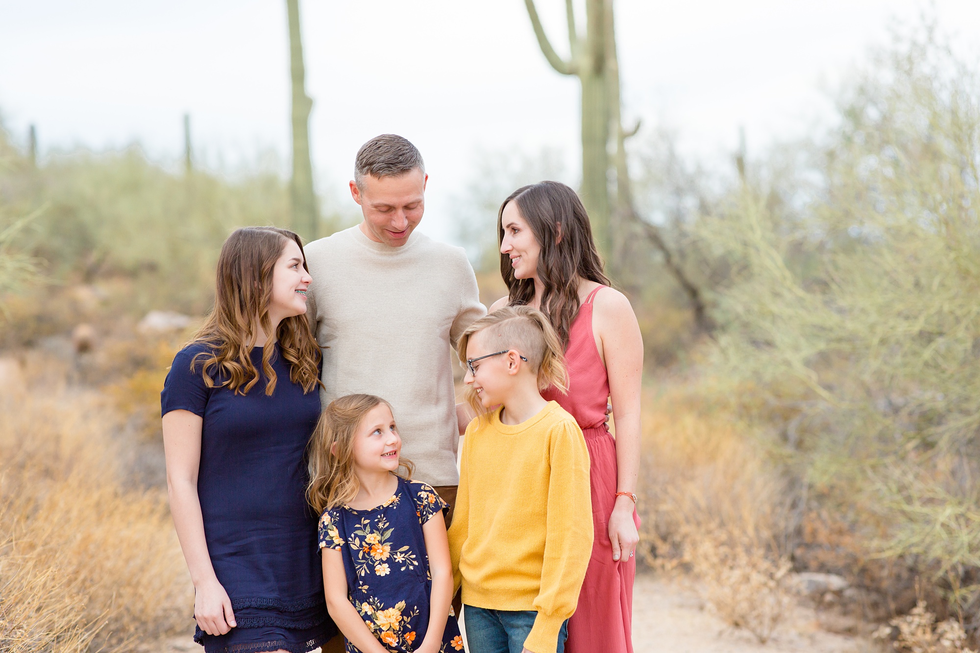 family with three daughters laughs during fall photos